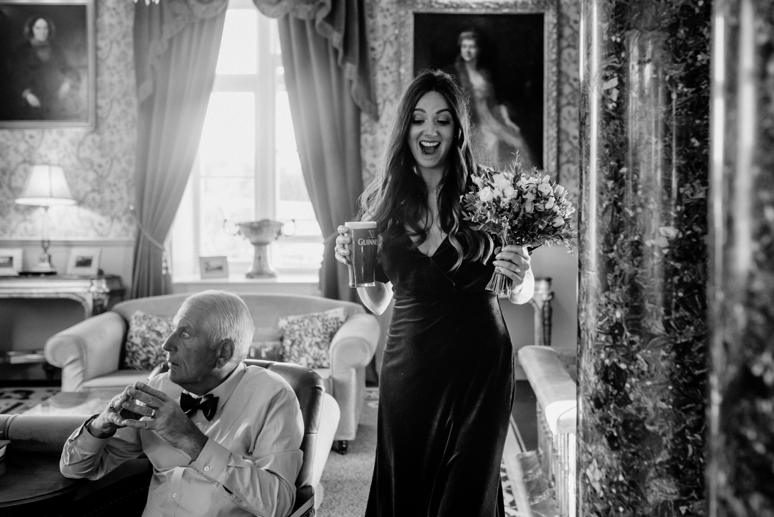 Wedding guest smiling while entering the dining room at Markree Castle with a bouquet of flowers