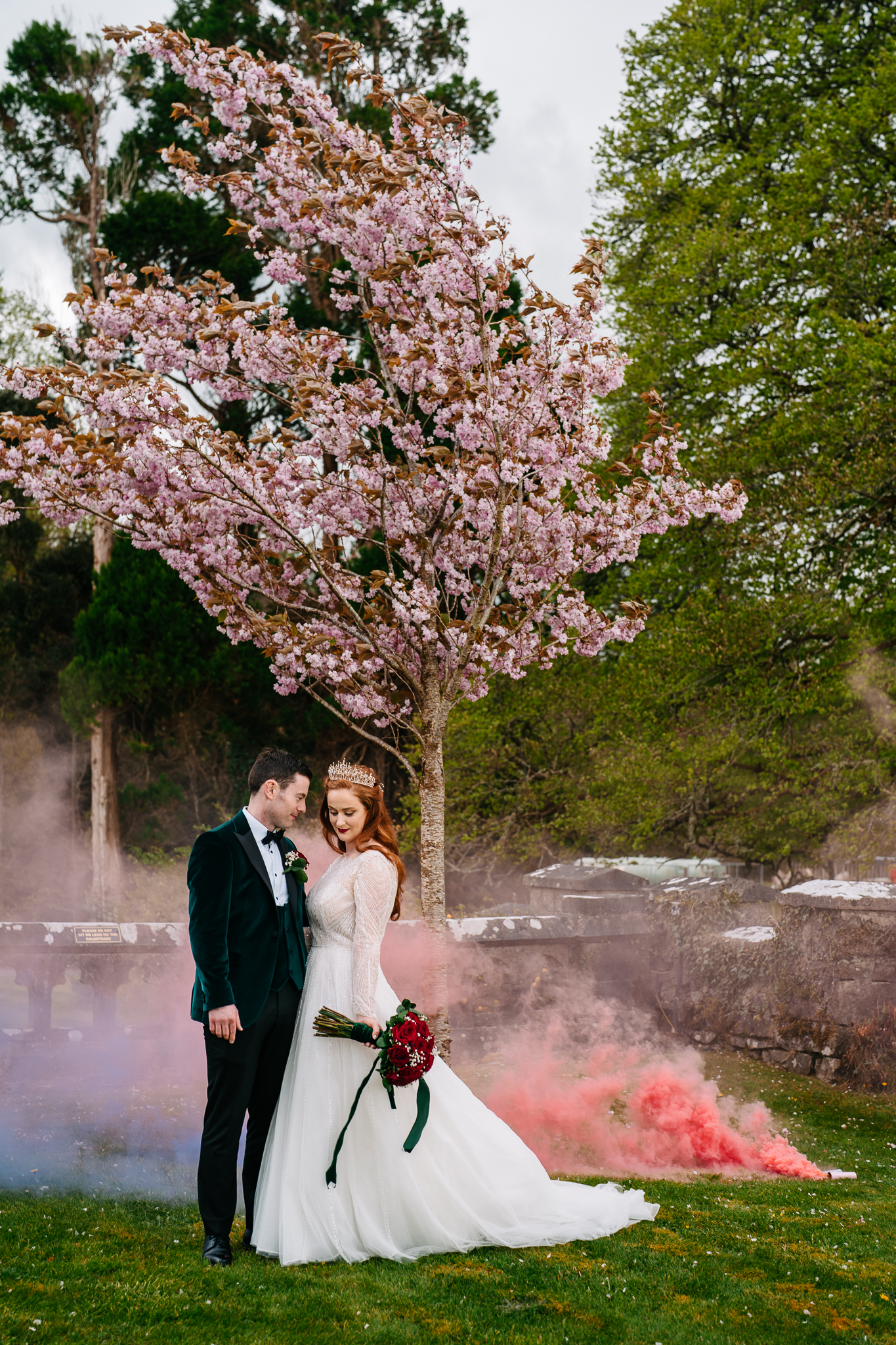 Bride and groom posing under blooming cherry blossom trees with romantic smoke effects during their Markree Castle wedding