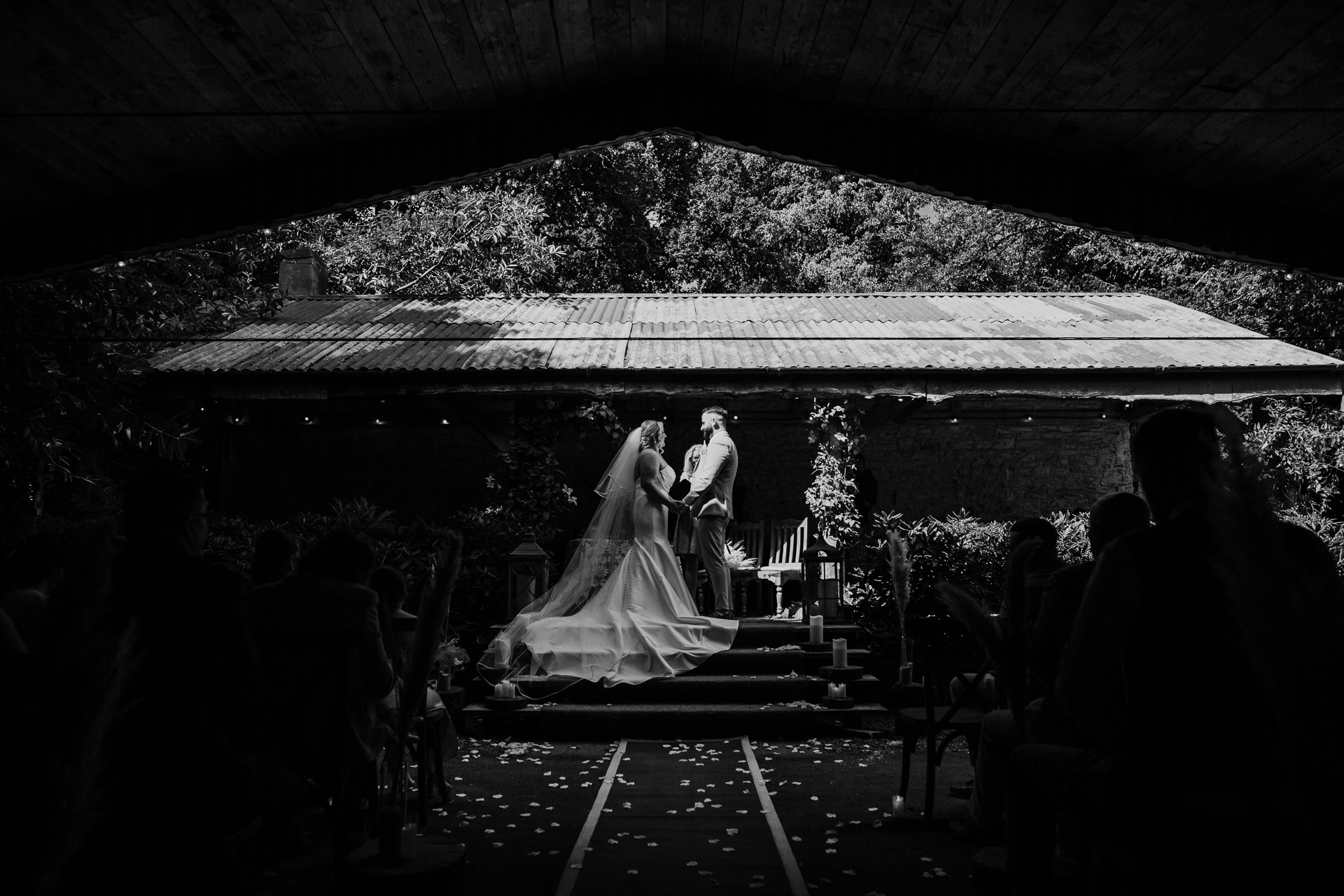 Black and white photo of bride and groom under a rustic pergola at Martinstown House