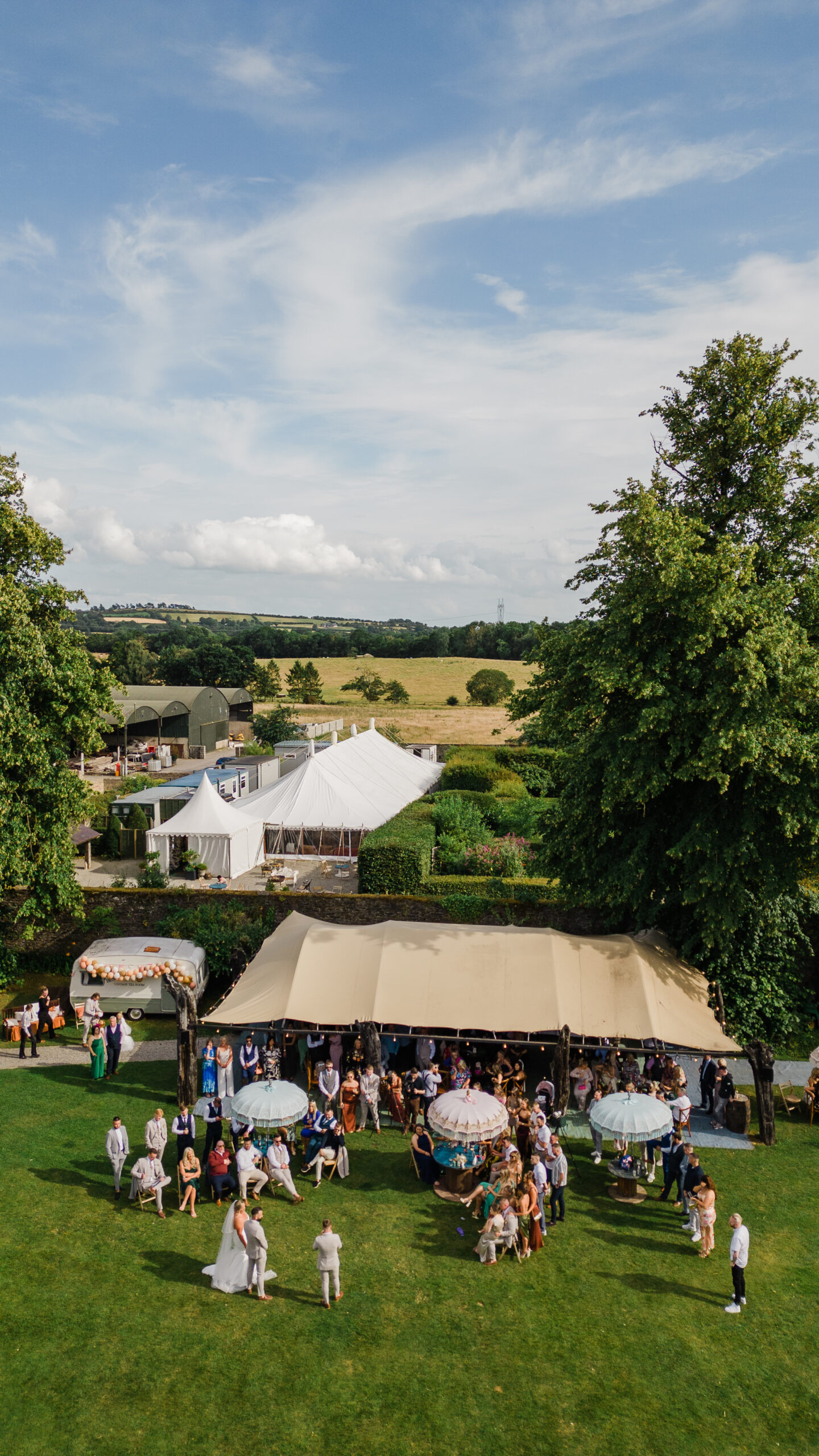 Outdoor wedding reception at Martinstown House with guests seated under parasols and canopy during a summer wedding in Ireland

