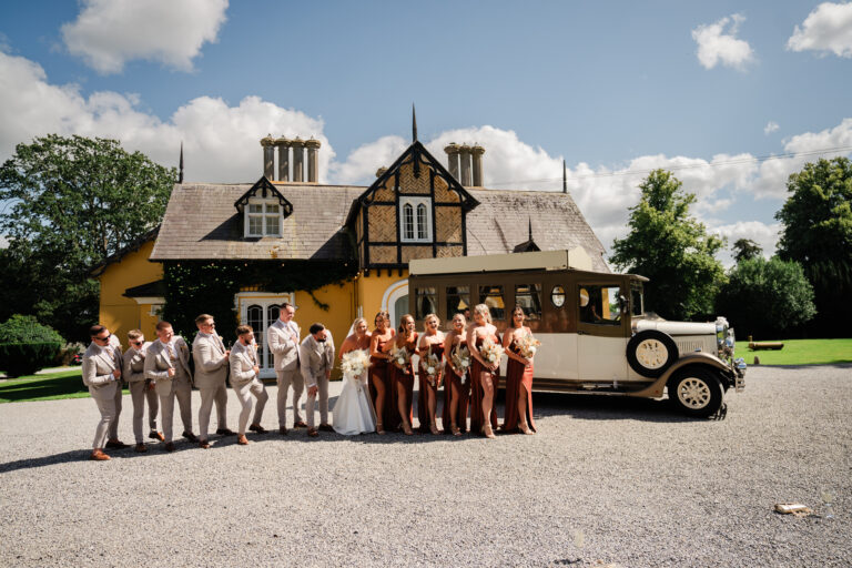 Bridal party and newlyweds in front of vintage wedding car at Martinstown House on a sunny summer day – Martinstown House Wedding Photographer