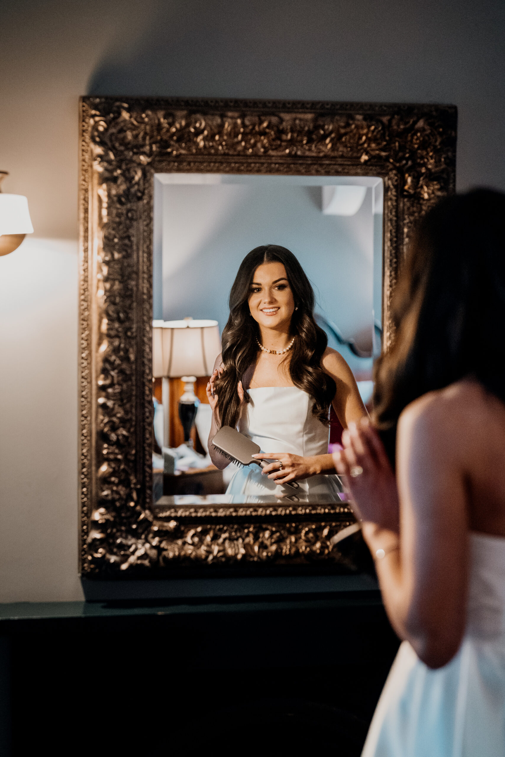 Bride looking at her reflection in an ornate mirror at Markree Castle’s bridal suite – captured by a Candid Wedding Photographer in Ireland.
