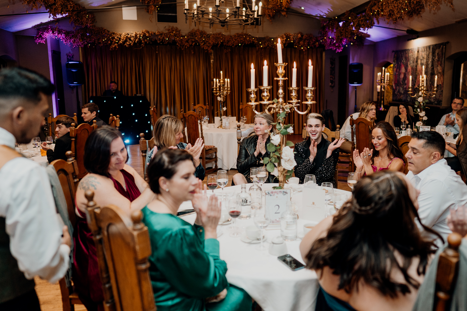 Guests sitting at round tables during wedding speeches at Barberstown Castle reception hall.