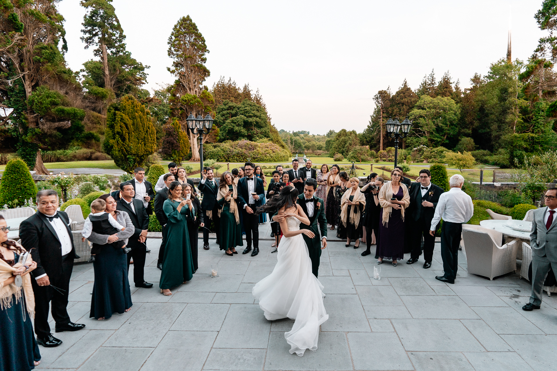 Bride and groom dancing on the garden terrace at Markree Castle during an outdoor wedding reception surrounded by guests

