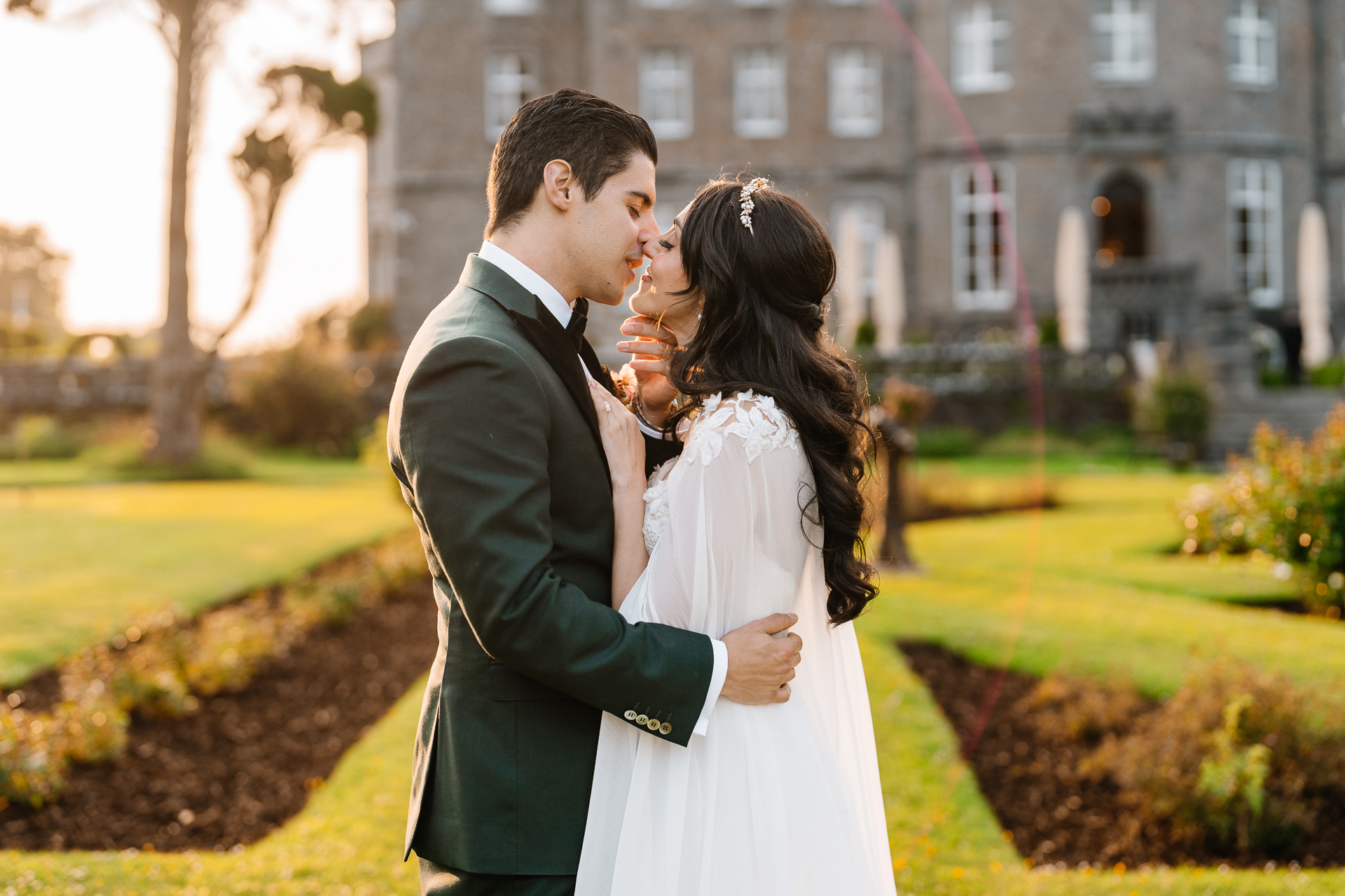 Bride and groom kissing during golden hour in front of Markree Castle after their wedding ceremony