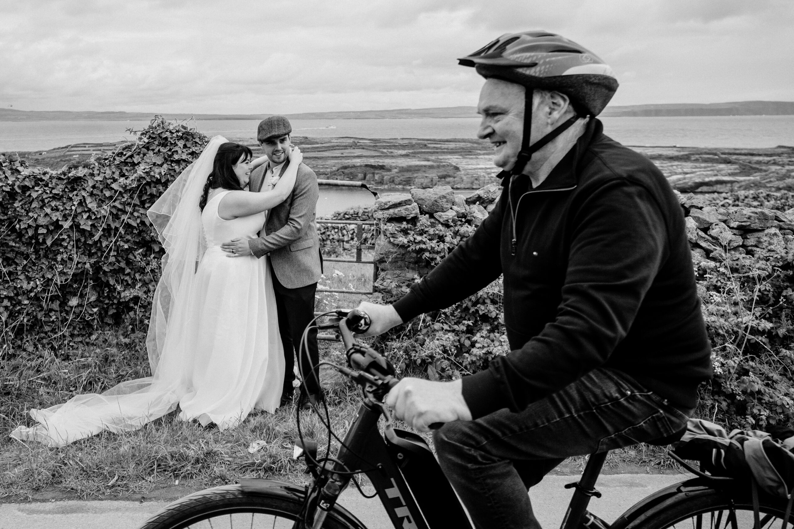 Bride and groom walk by a local man on a bicycle near Loch Mór, Inisheer – Aran Islands elopement