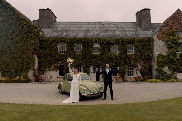 Bride and groom celebrating in front of Cloughjordan House with vintage car – Cloughjordan House Wedding Cost Guide