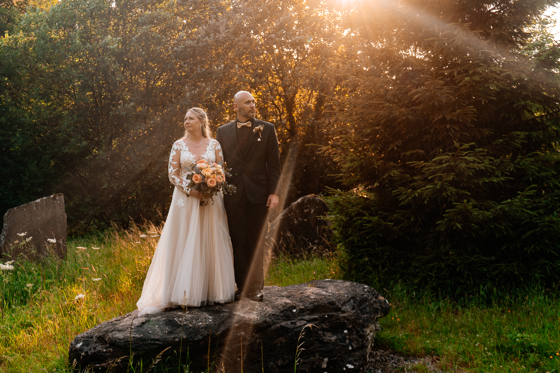 Bride and groom walking across Kinnitty Suspension Bridge and forest paths at sunset near Kinnitty Castle Hotel.