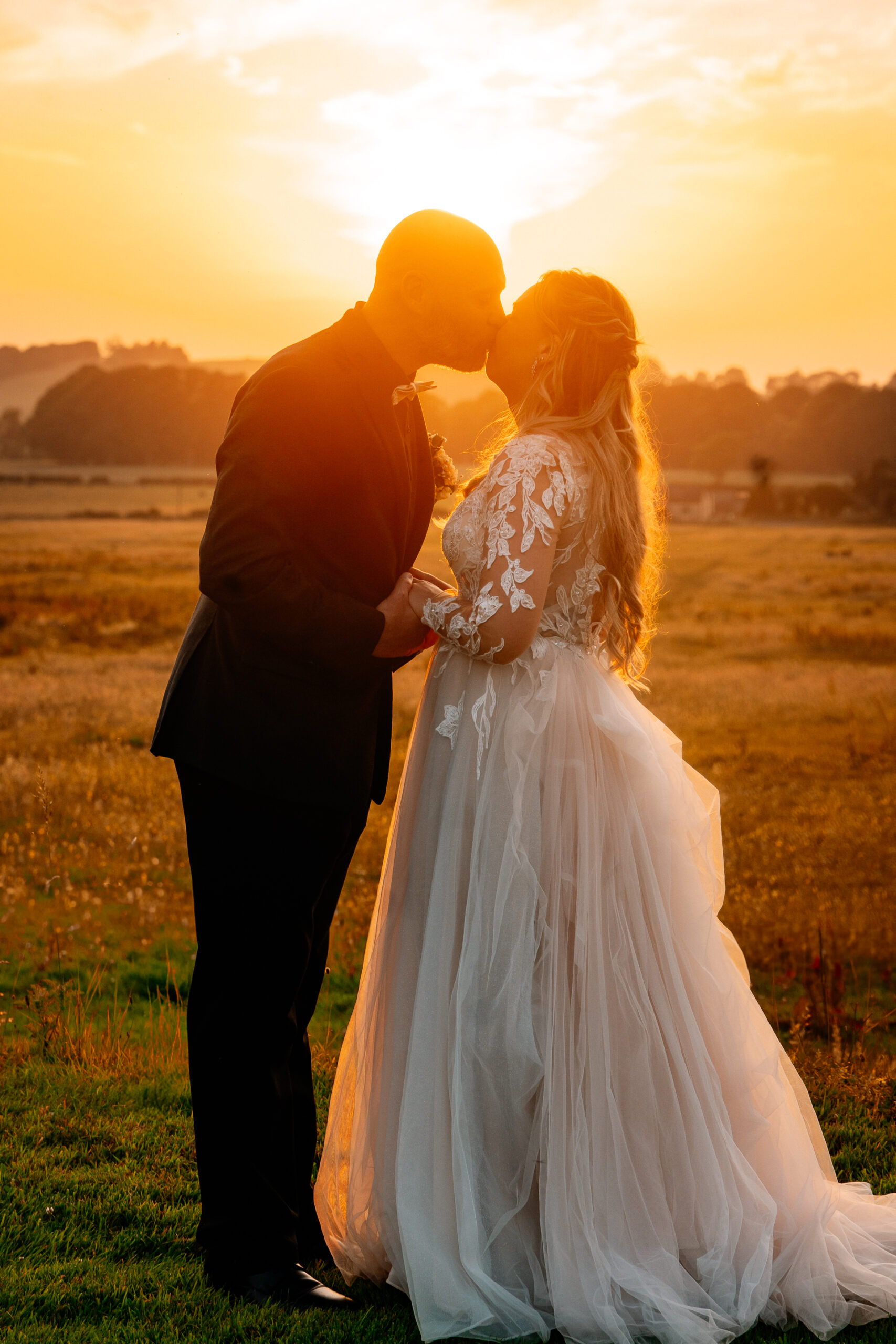 Bride and groom walking across Kinnitty Suspension Bridge and forest paths at sunset near Kinnitty Castle Hotel.
