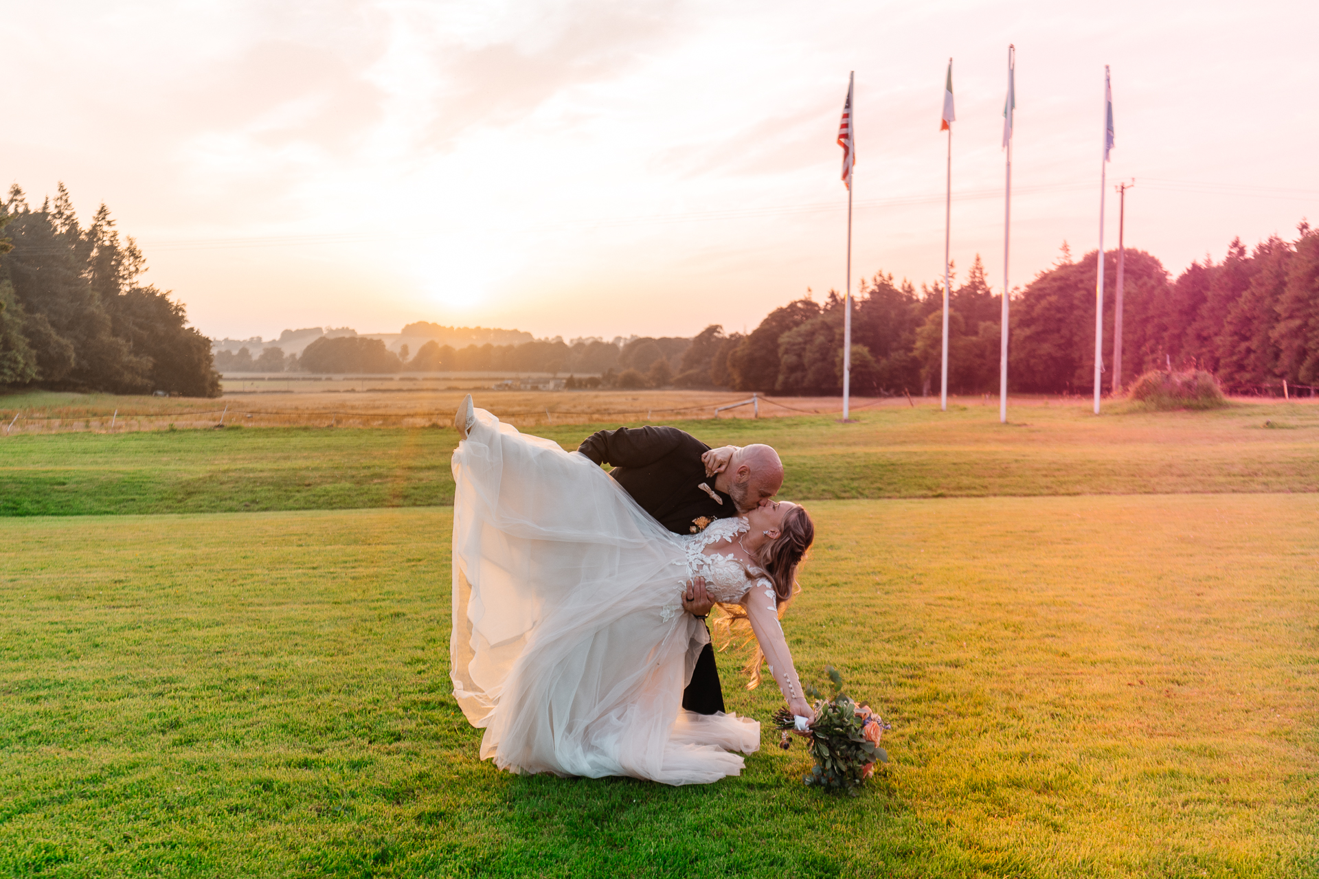 Bride and groom kissing at sunset in front of flags – Kinnitty Castle Hotel wedding