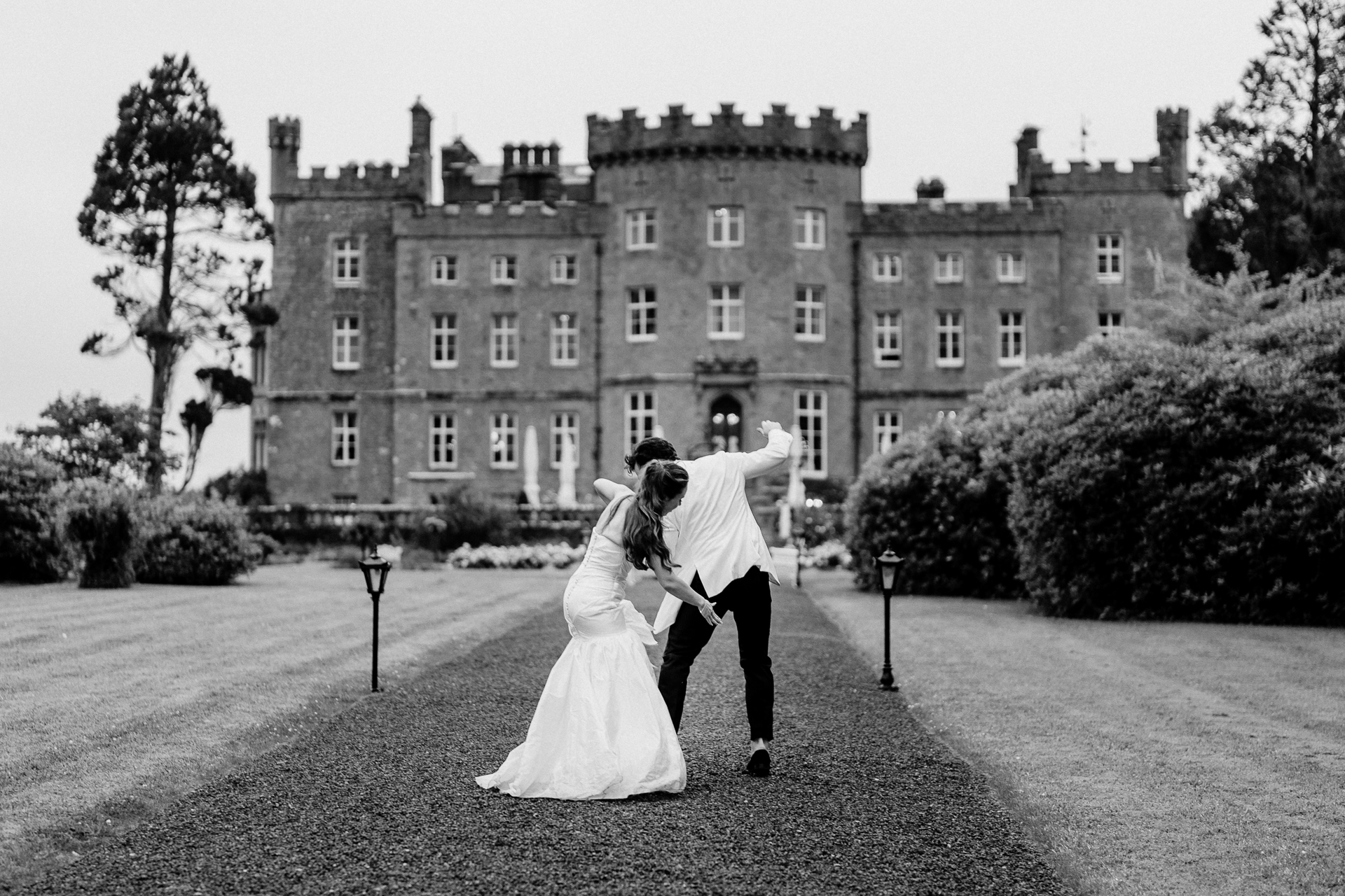 Bride and groom walking hand in hand in front of Markree Castle – black and white wedding photo

