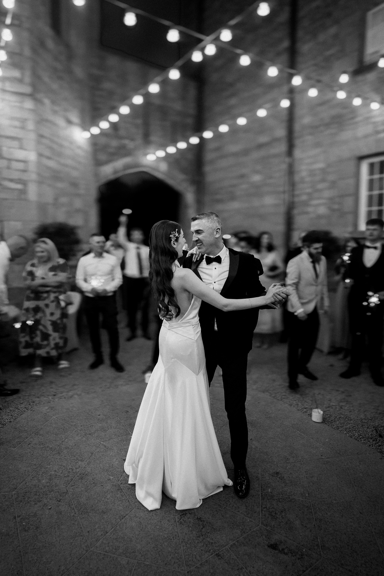 Bride and groom dancing under string lights during sparkler moment in Markree Castle courtyard  