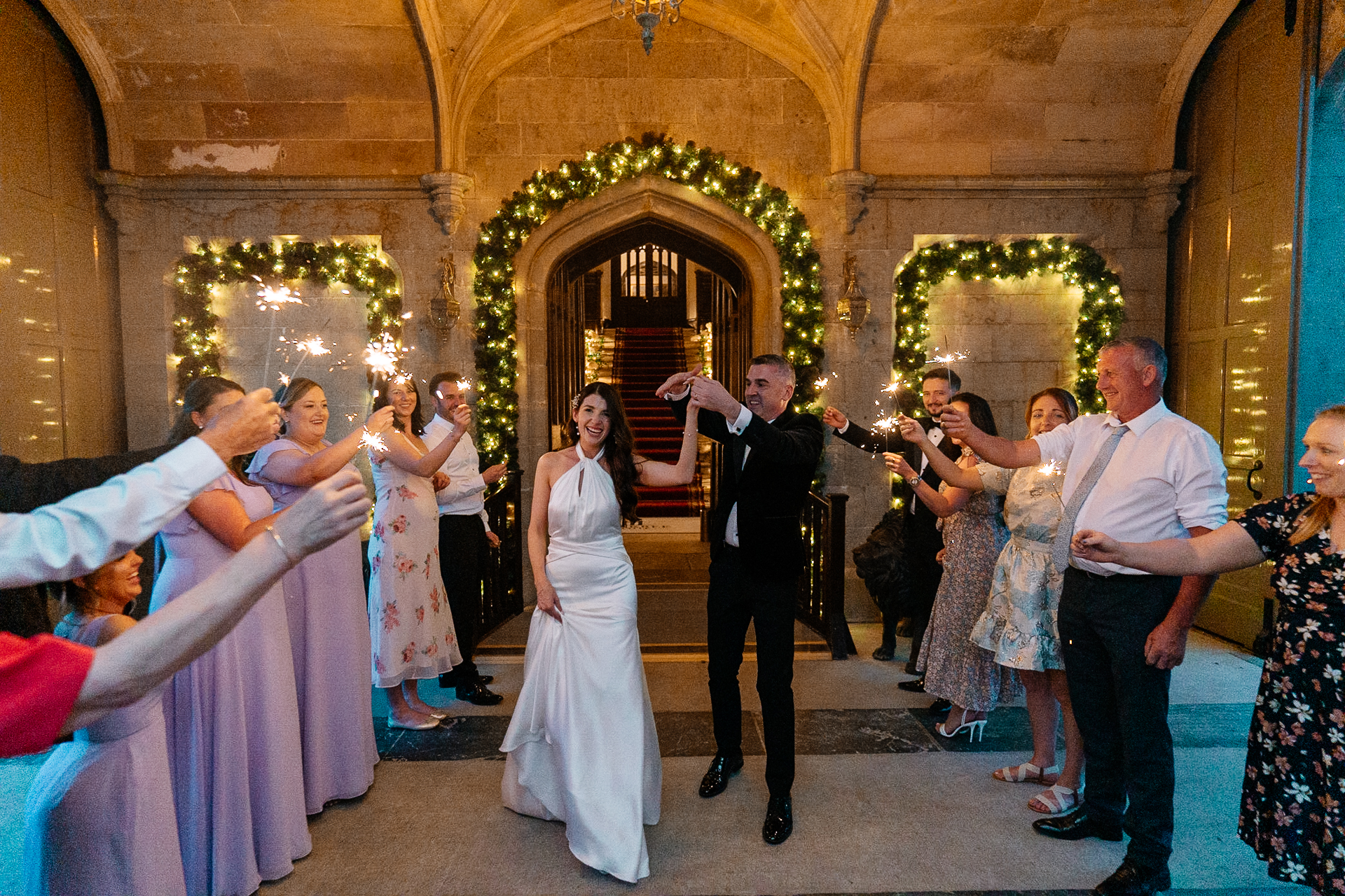 Bride and groom walking through a sparkler tunnel at night under the archway at Markree Castle