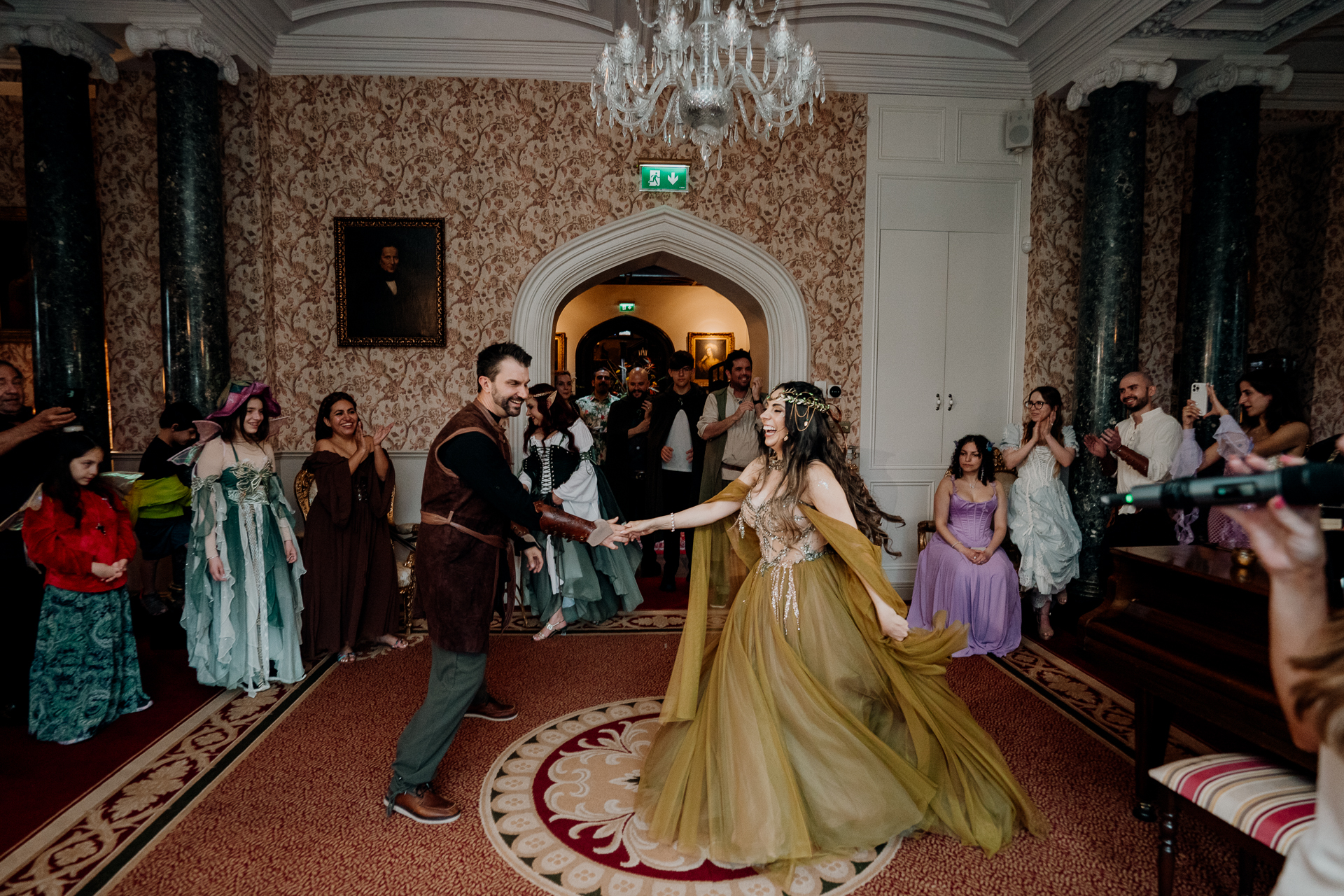 Bride in golden fantasy gown with long train entering the grand dining hall at Markree Castle during rehearsal dinner in Sligo, Ireland