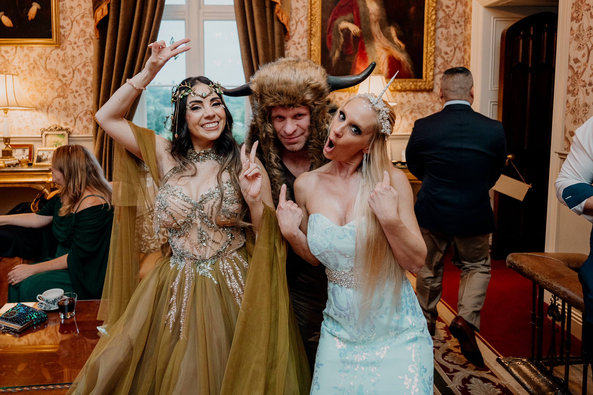 Three women in elegant fantasy-inspired gowns smiling together during the rehearsal dinner at Markree Castle, Sligo, Ireland