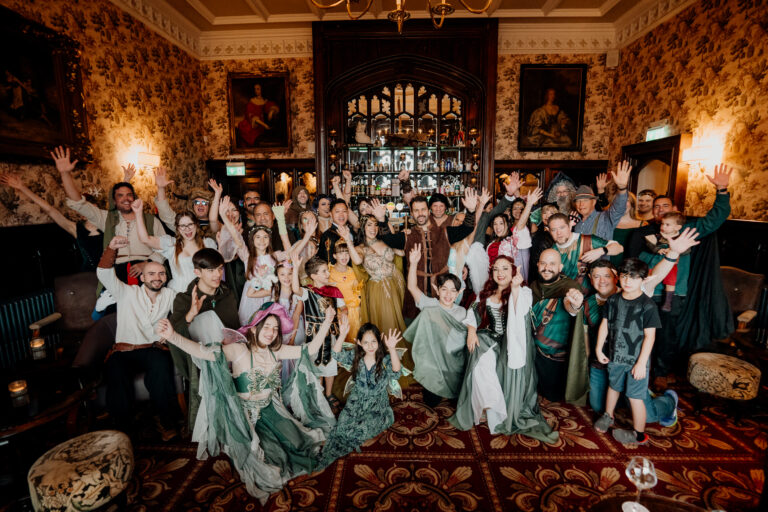 Fantasy-style rehearsal dinner group photo at Markree Castle bar with guests in costumes before Irish dancing