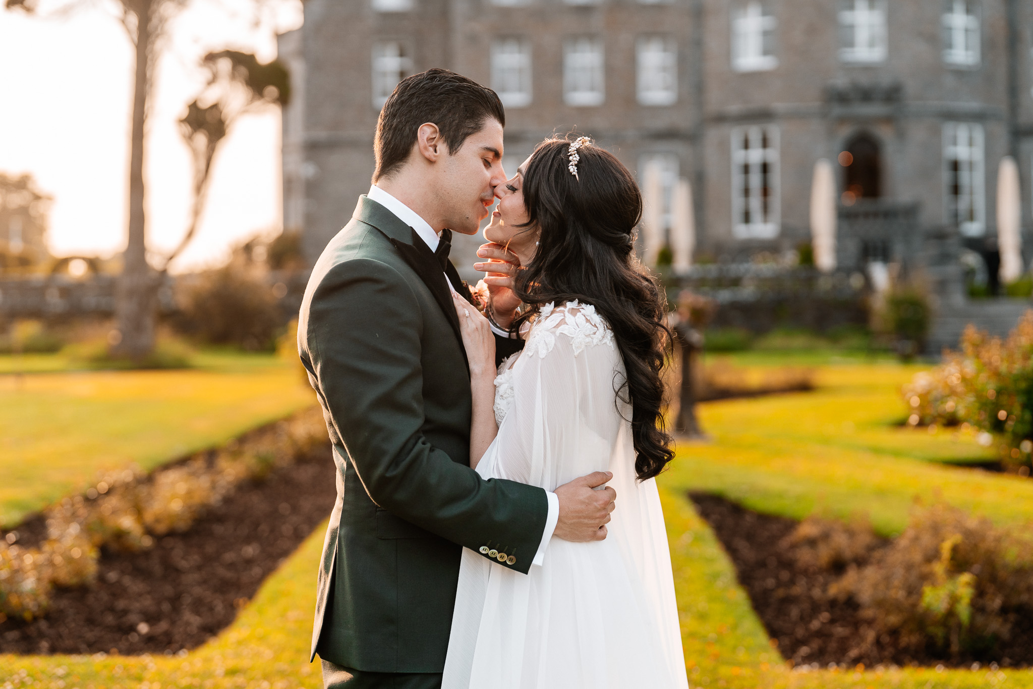 Bride and groom kissing at sunset in front of Markree Castle