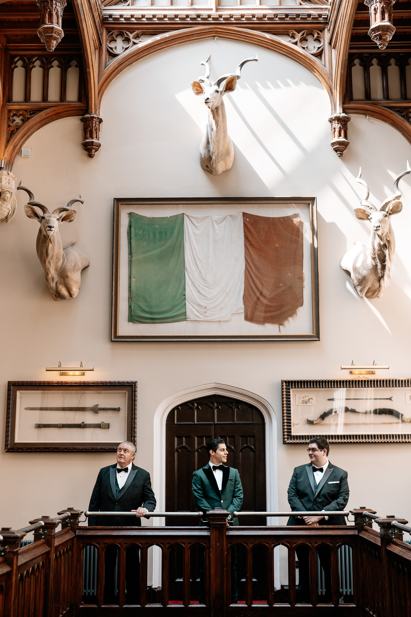 Groom standing beneath the flags inside Markree Castle before the wedding ceremony