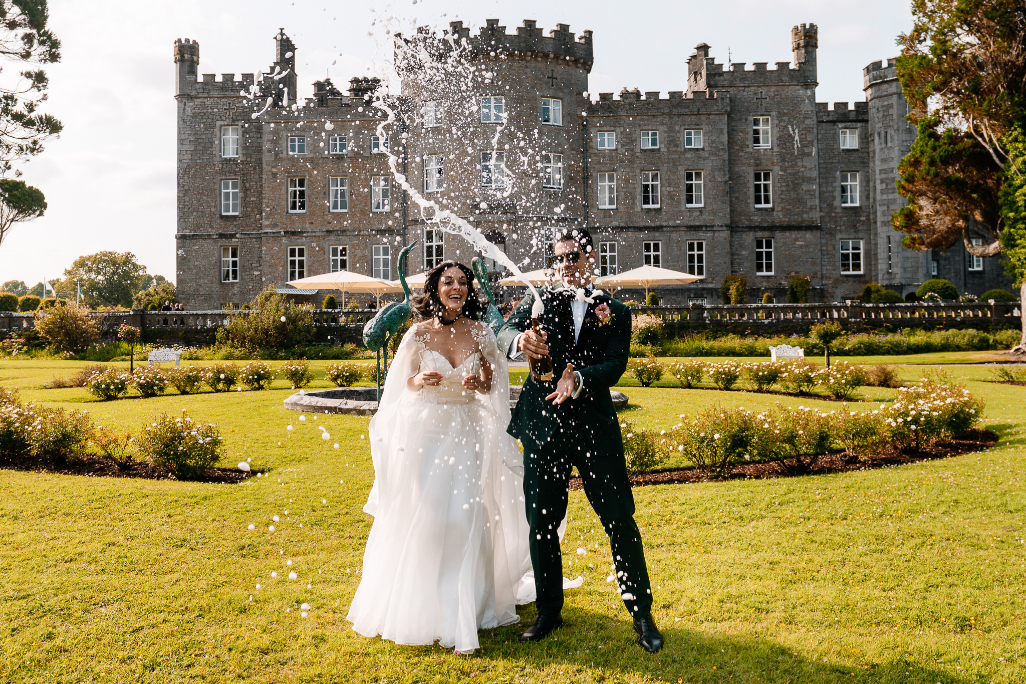 Newlyweds spraying champagne in front of Markree Castle after their wedding ceremony