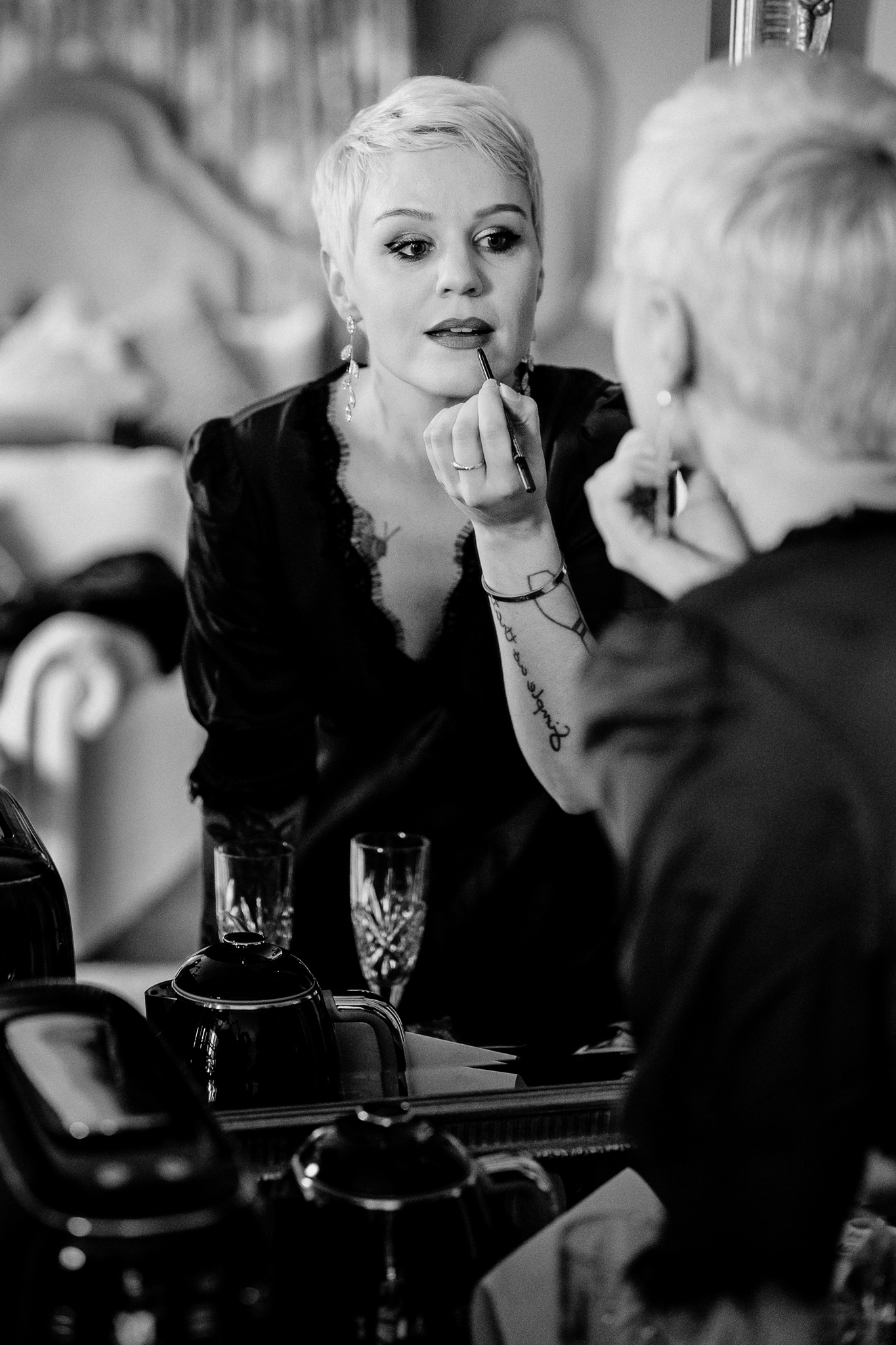 Black and white photograph of Meagan having her makeup finished beside a mirror at Markree Castle
