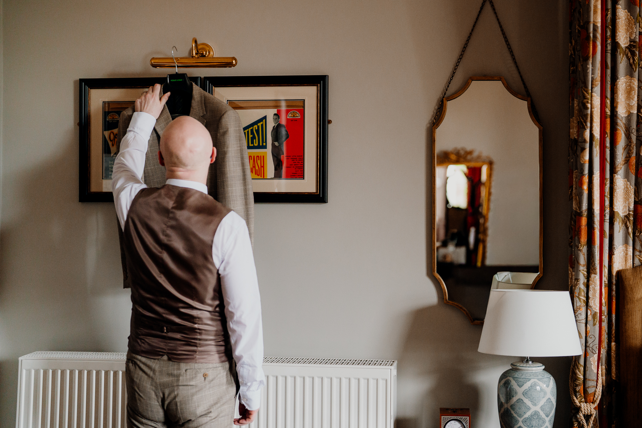 Groom adjusting his wedding outfit in front of a mirror in the Johnny Cash Room at Markree Castle