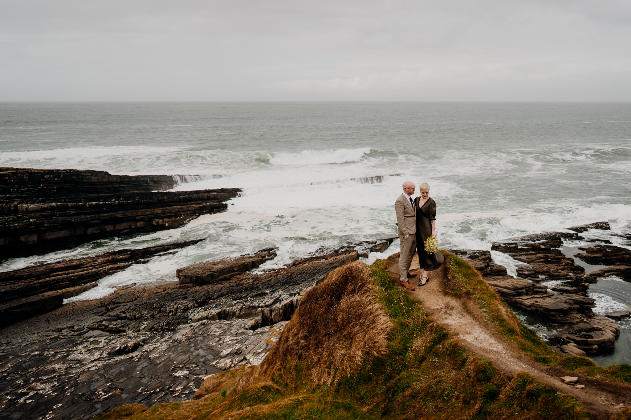 Wedding couple standing on the rugged coastal cliffs of Mullaghmore Head overlooking the Atlantic Ocean