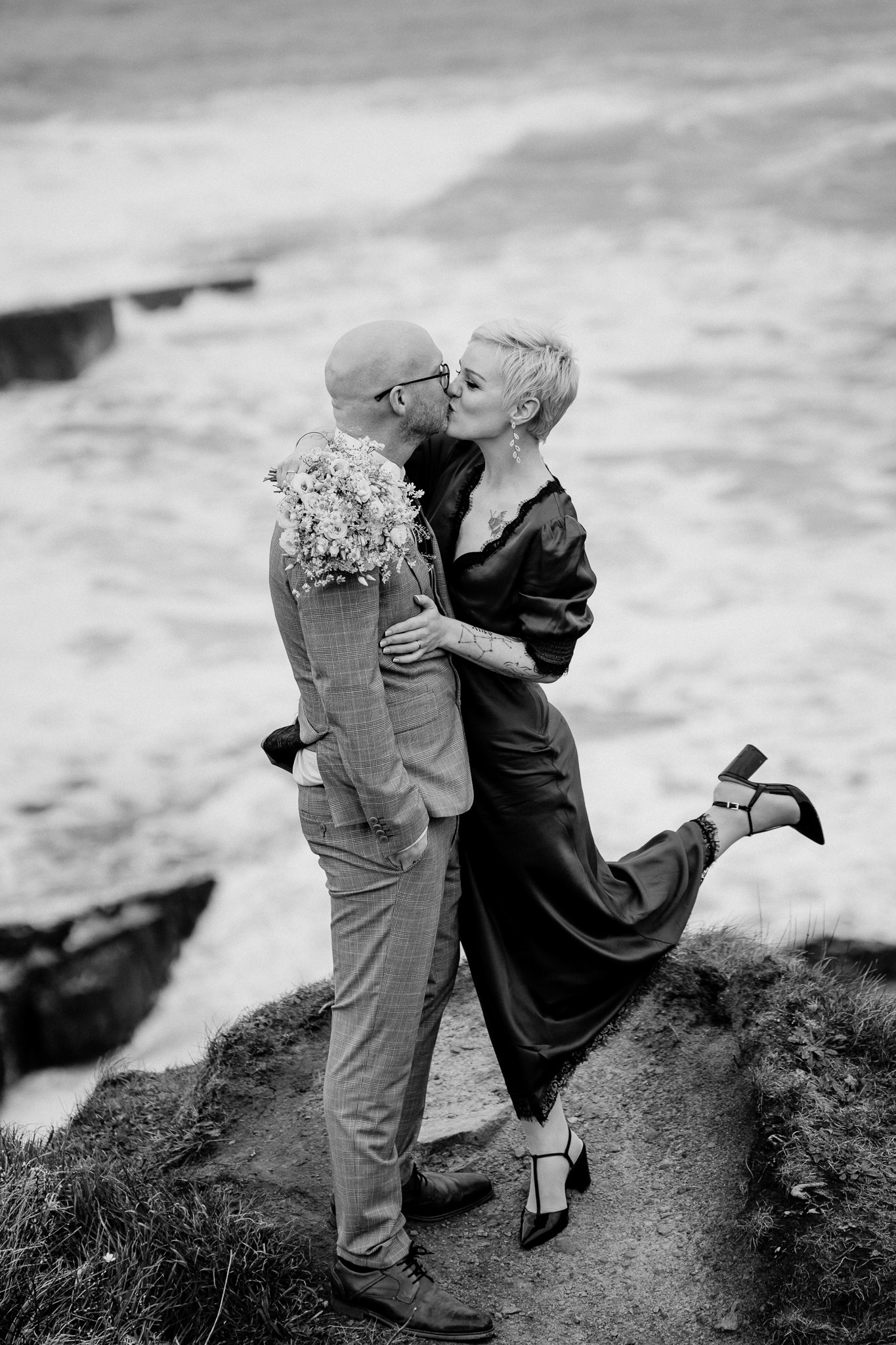 Black and white wedding portrait of newlyweds kissing on the rocky coast at Mullaghmore Head
