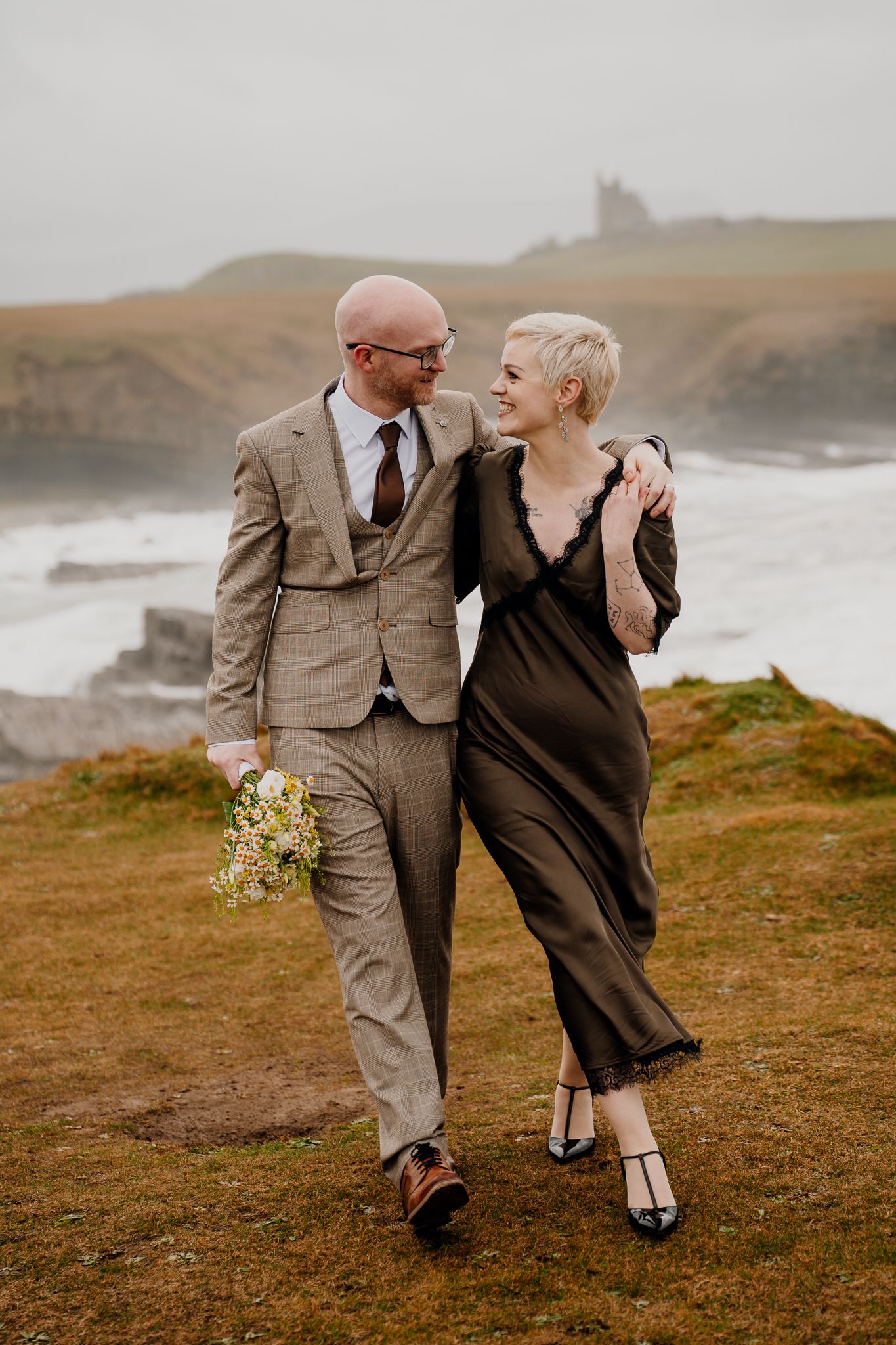 Newly married couple walking along the grassy Mullaghmore Head coastline in County Sligo