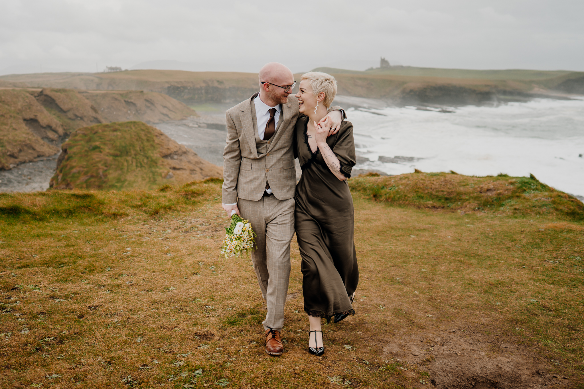 Relaxed newlywed couple walking together at Mullaghmore Head with the Atlantic coast behind them