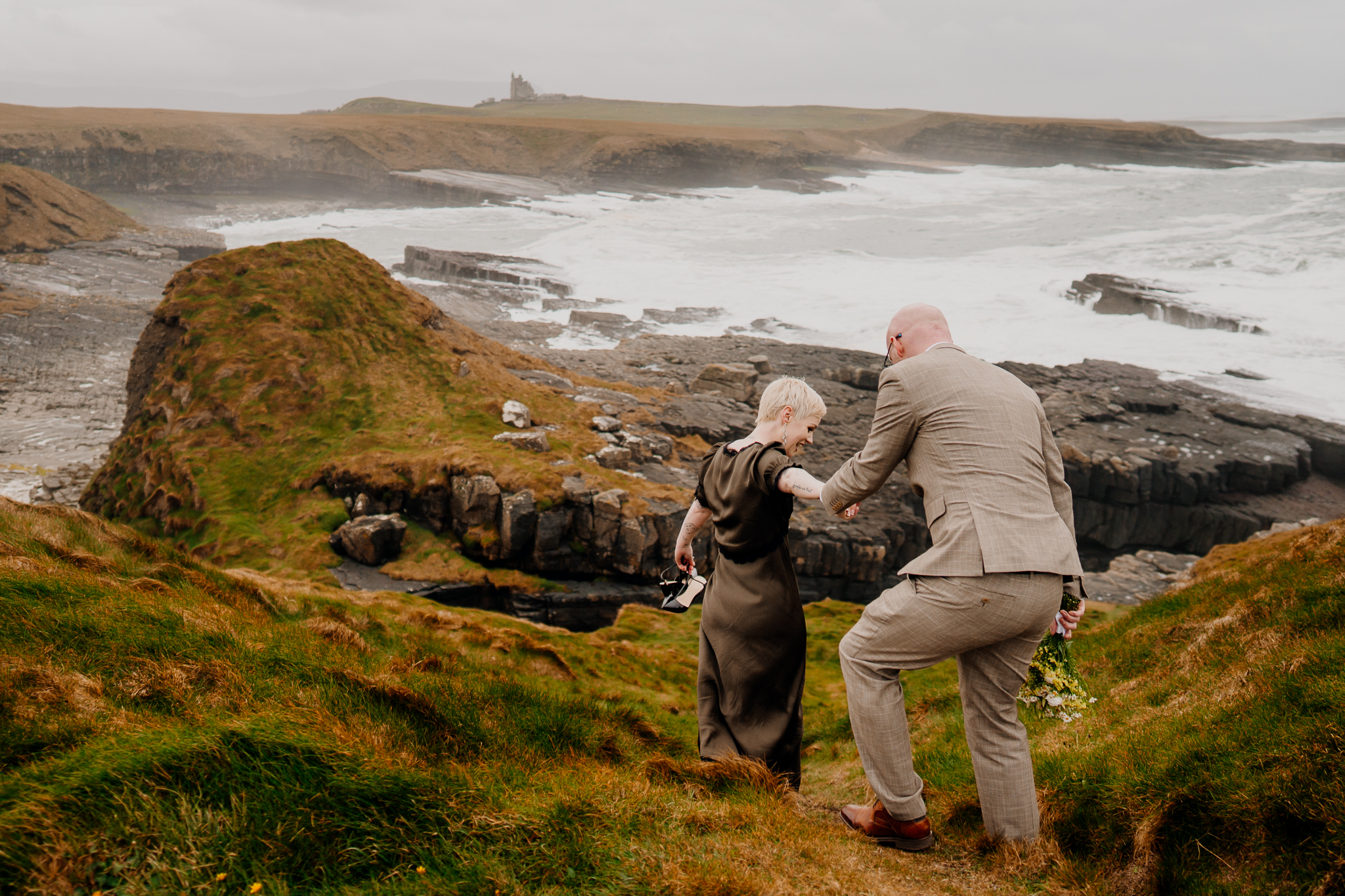 Newly married couple walking down the grassy coastal headland at Mullaghmore in Sligo