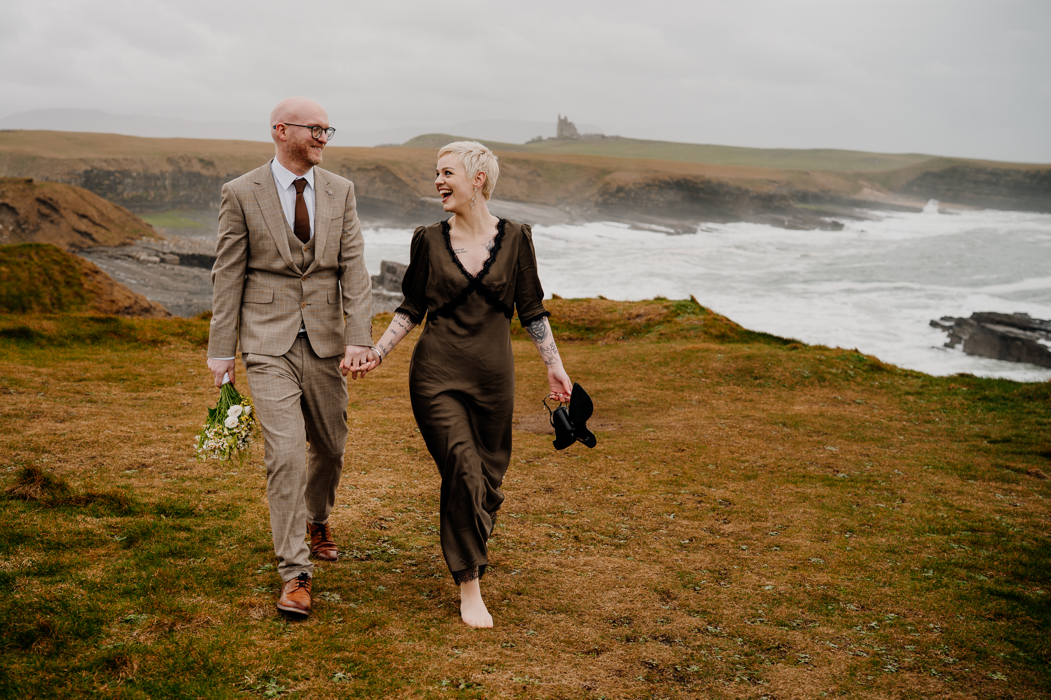 Groom lifting his bride at Mullaghmore Head with Classiebawn Castle visible in the distance