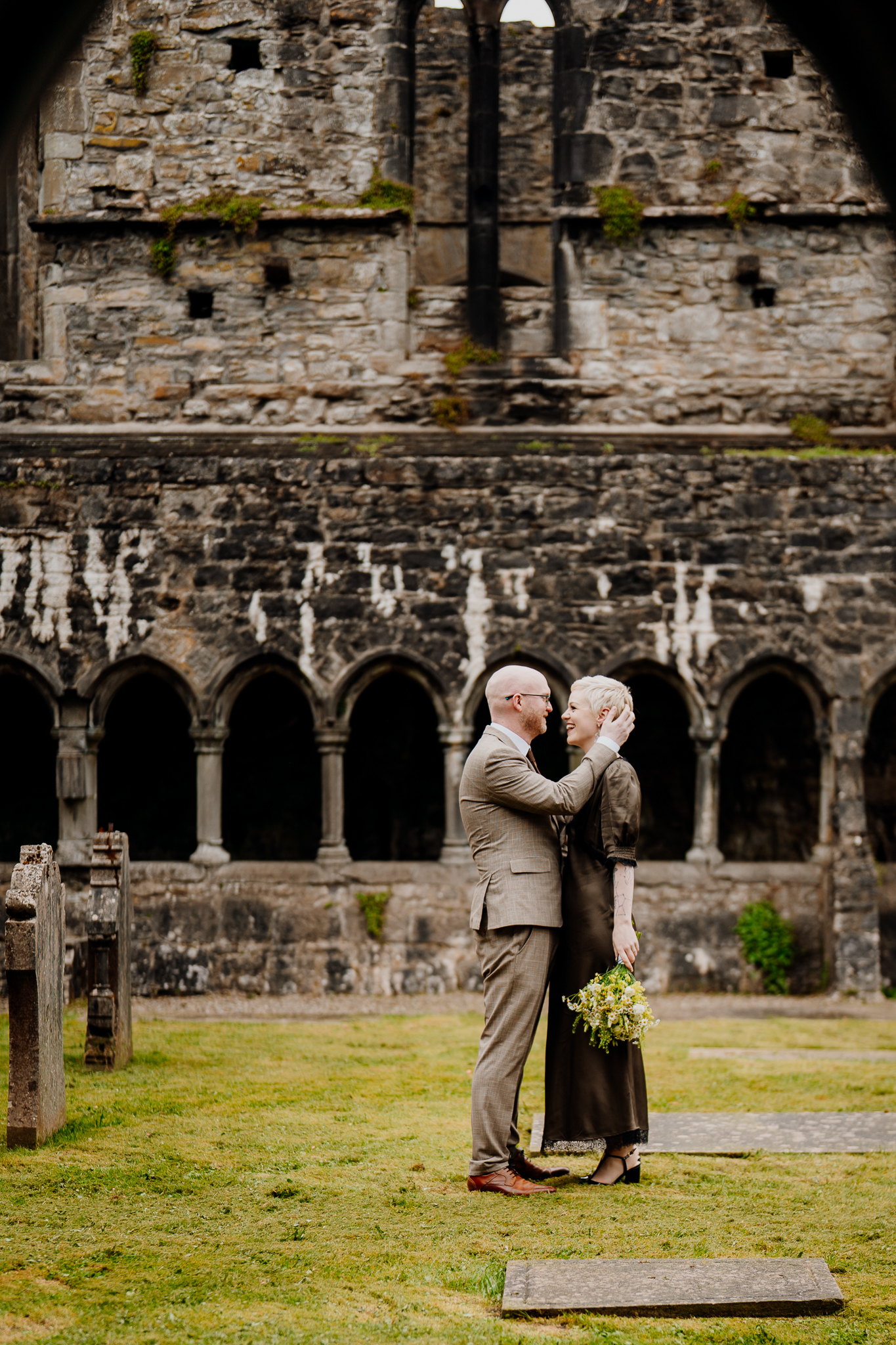 Newlyweds embracing beneath the medieval stone arches of Sligo Abbey Ireland