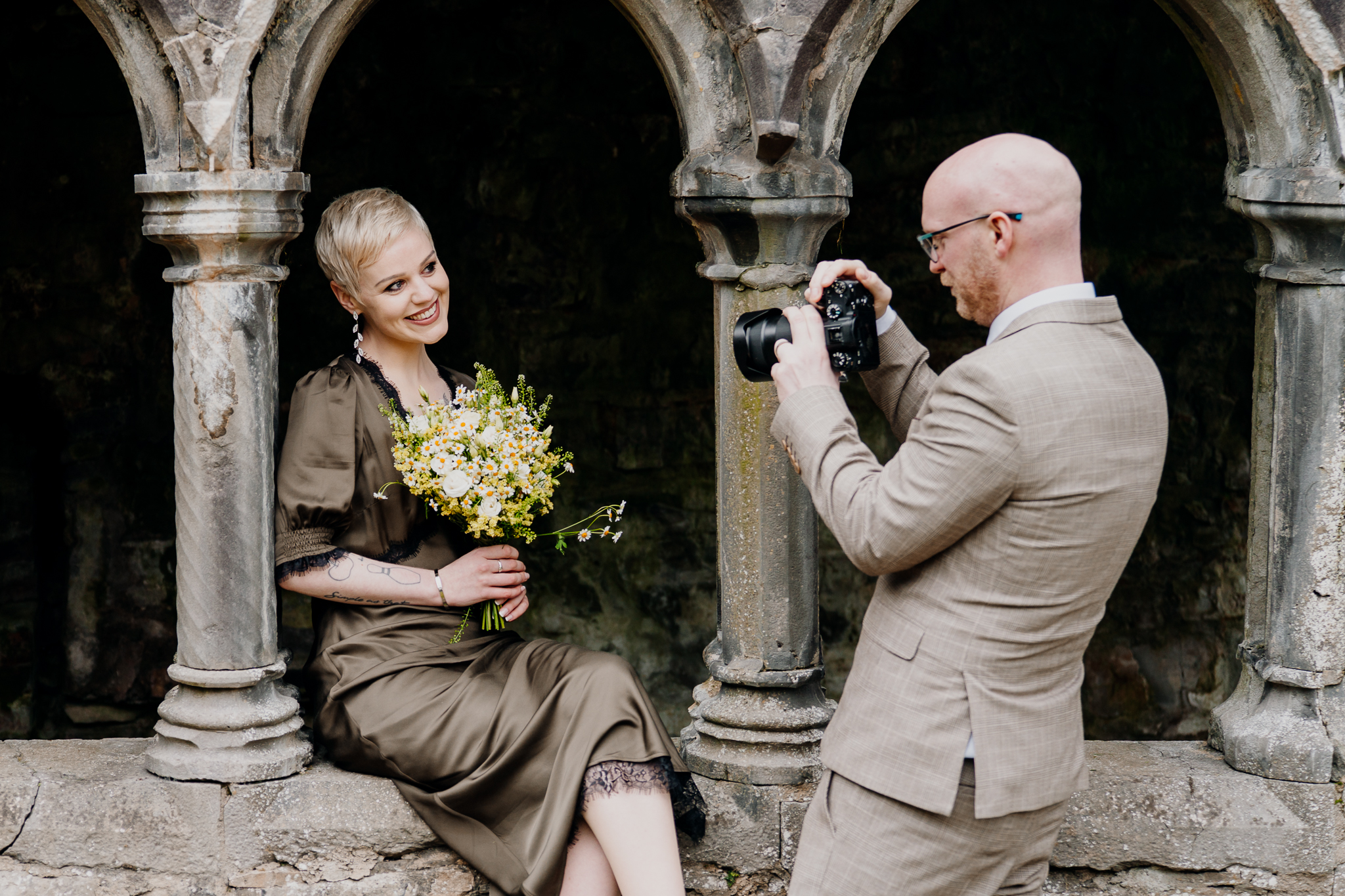 Bride holding her colourful bouquet while being photographed at Sligo Abbey