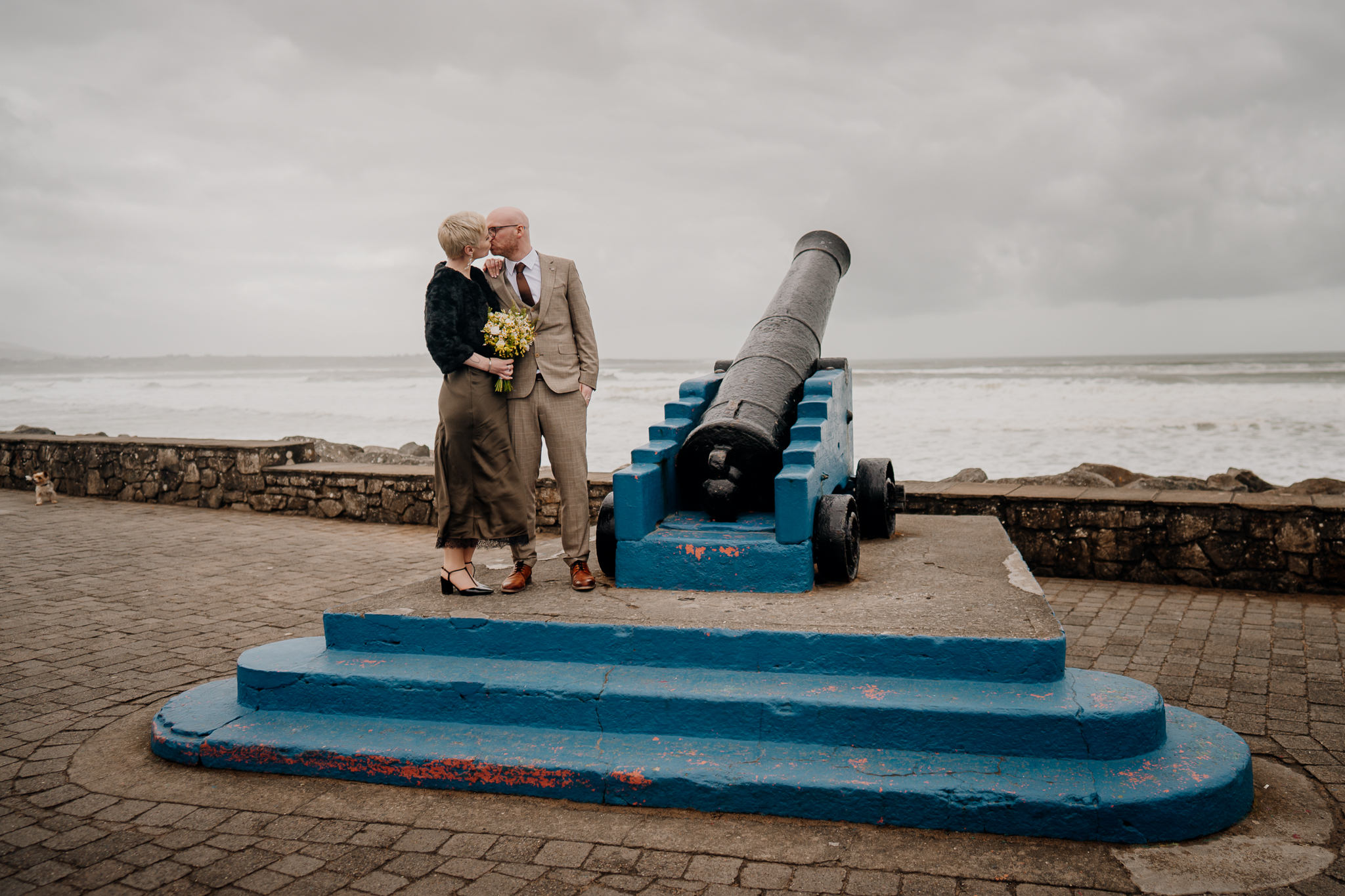 Intimate wedding couple kissing beside the historic cannon on Strandhill promenade in Sligo