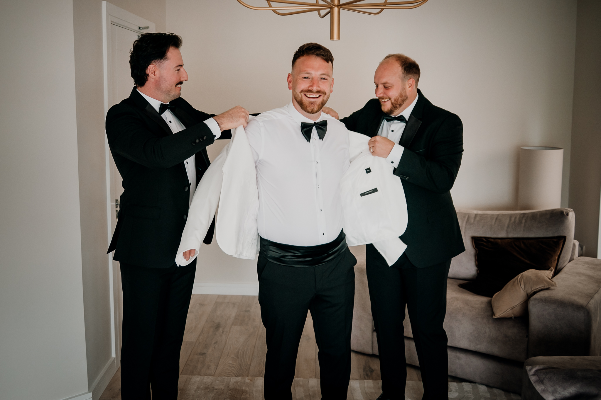 Groomsmen helping groom Michael with his jacket at Markree Castle