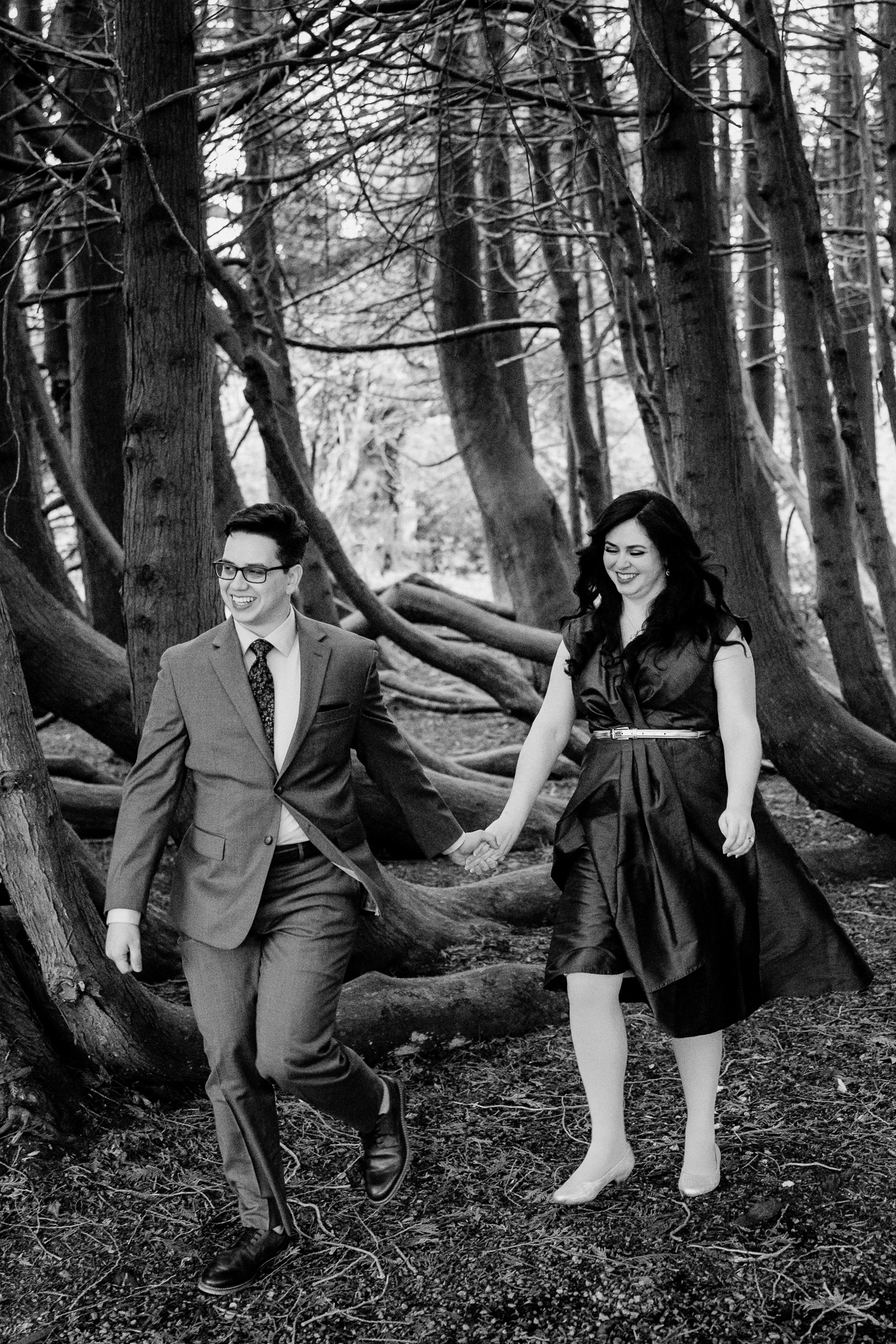 Black-and-white engagement photograph of a couple holding hands among the trees at Markree Castle in County Sligo, Ireland.