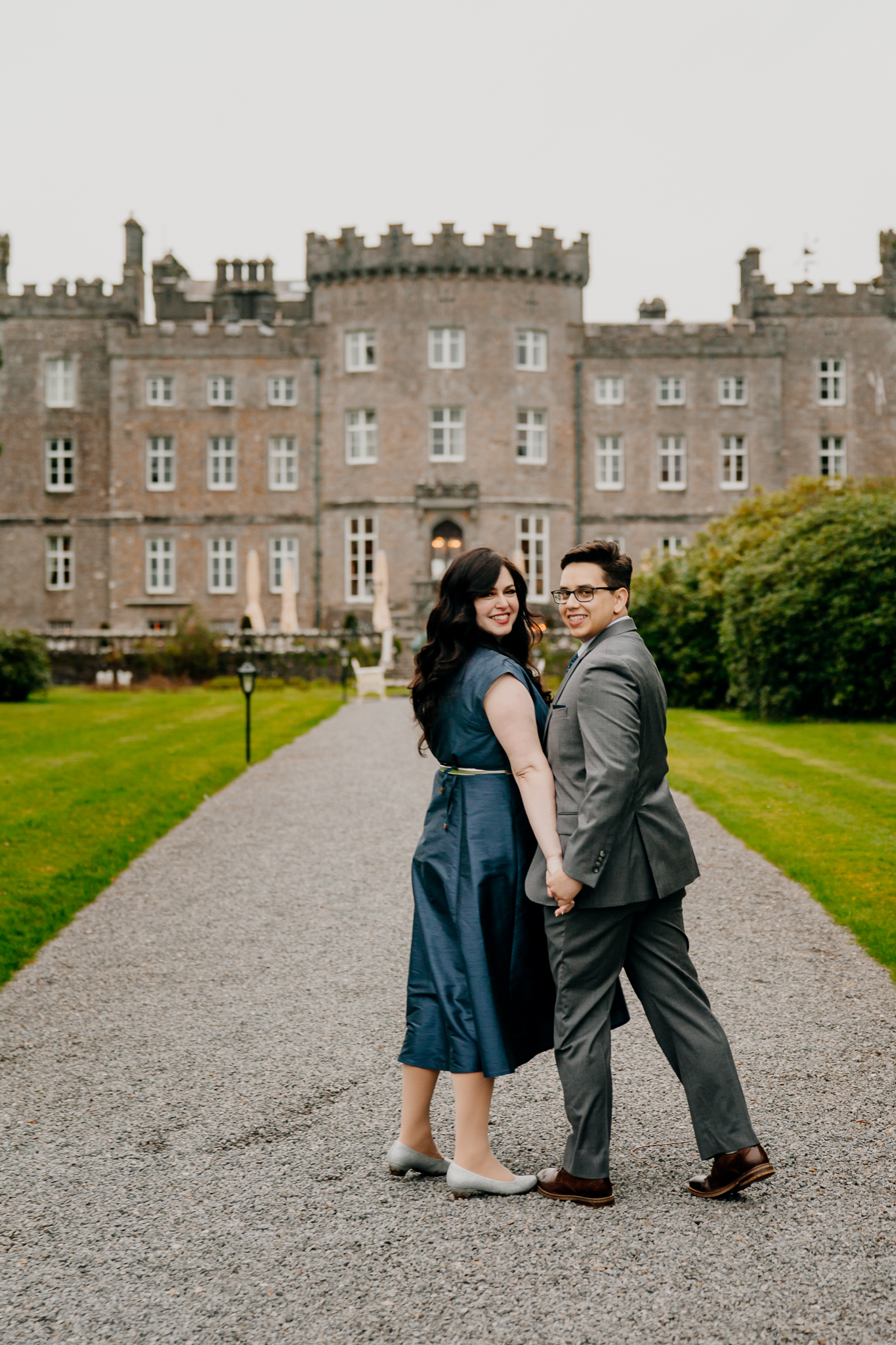 Newly engaged couple embracing in the gardens with the historic Markree Castle building in the background, Sligo, Ireland.