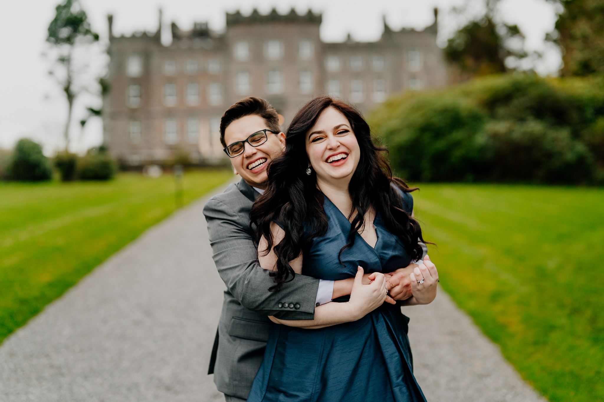 Happy newly engaged couple smiling in the gardens with Markree Castle in the background after their surprise proposal in Sligo, Ireland.