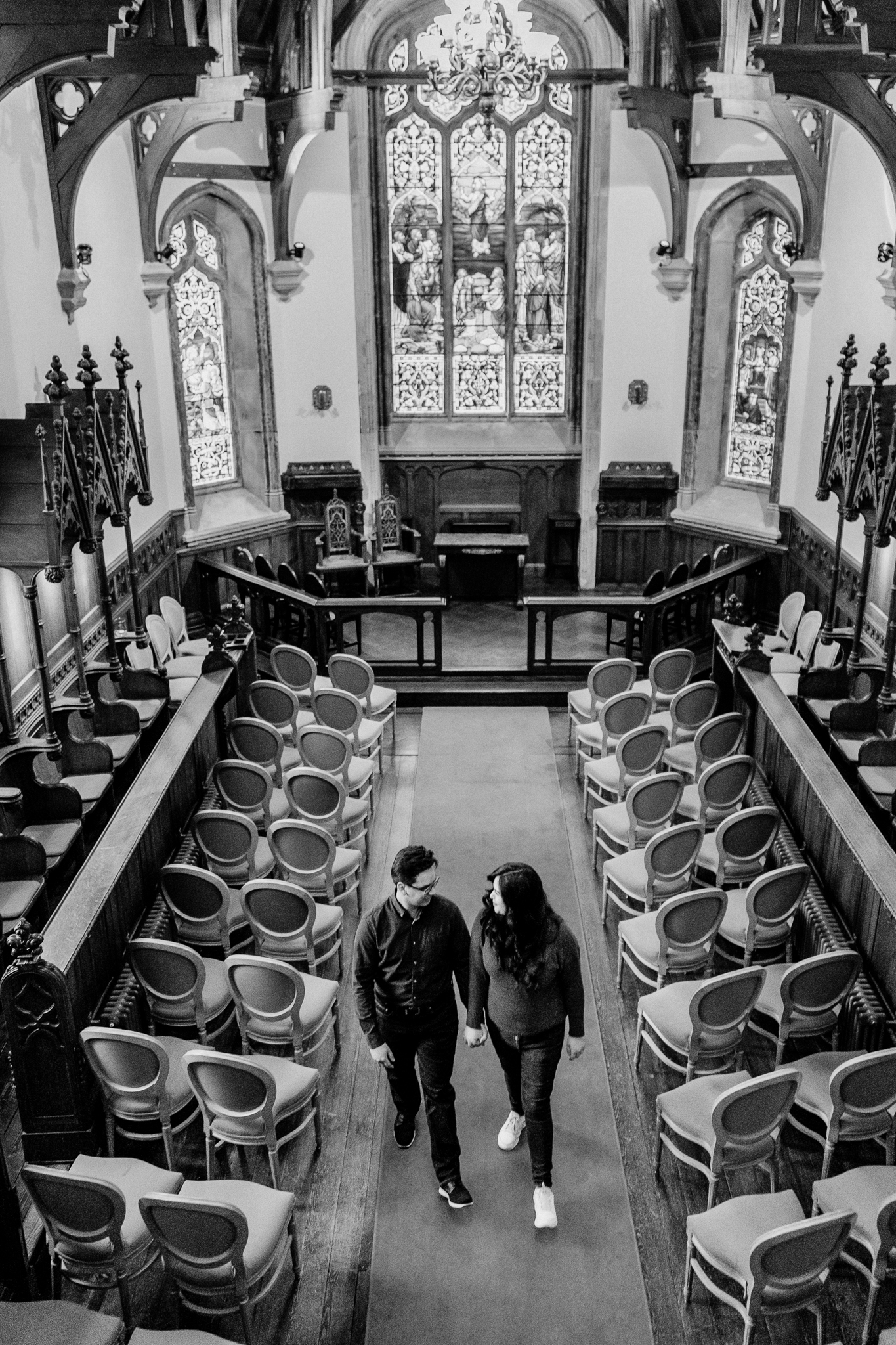 Black-and-white photograph of a couple during their surprise proposal inside the historic Markree Castle chapel, surrounded by wooden pews and stained glass.