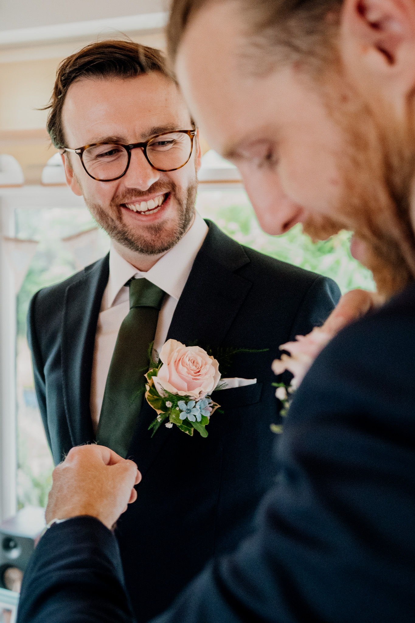 Candid black and white groom preparations with family
