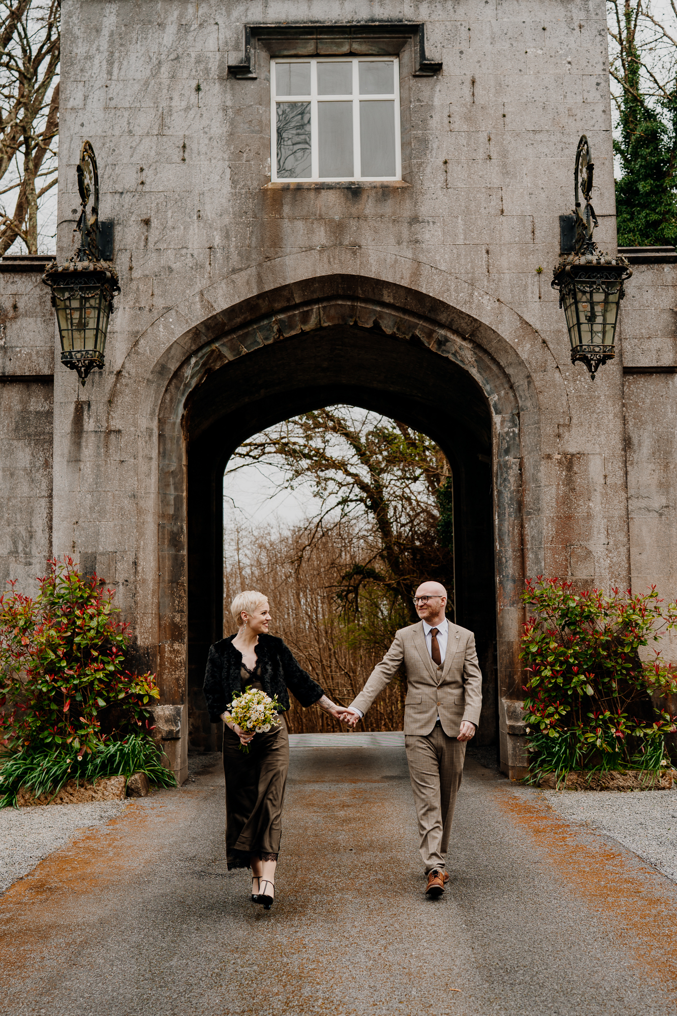 Newly married couple walking beneath the historic entrance arch at Markree Castle Sligo