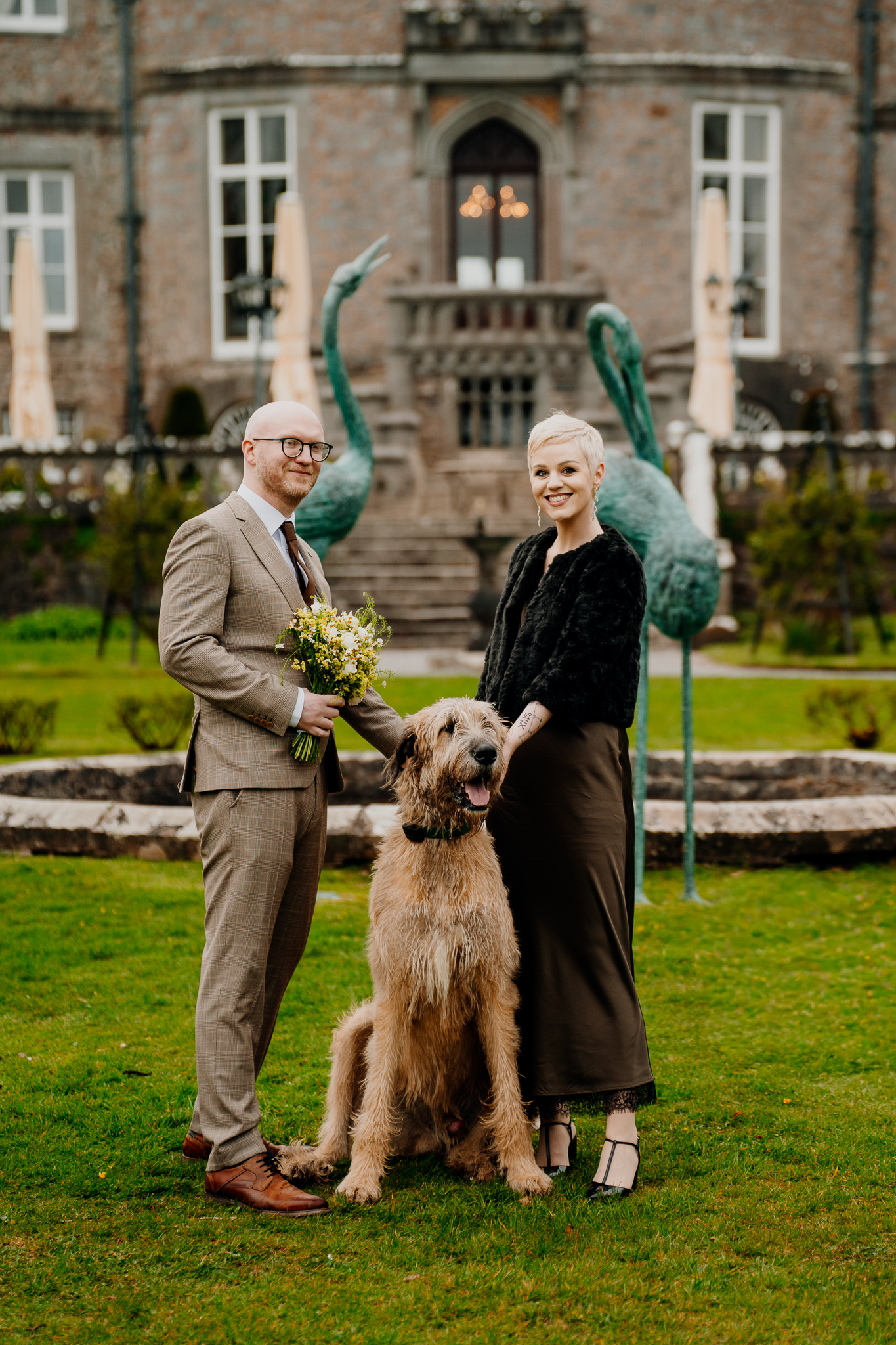 Newlyweds sharing a joyful moment with Fionn the Irish Wolfhound in Markree Castle gardens