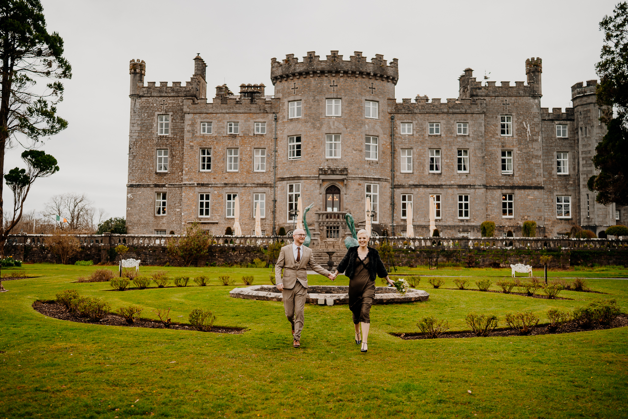 Newlyweds walking across the formal lawn in front of Markree Castle in Sligo