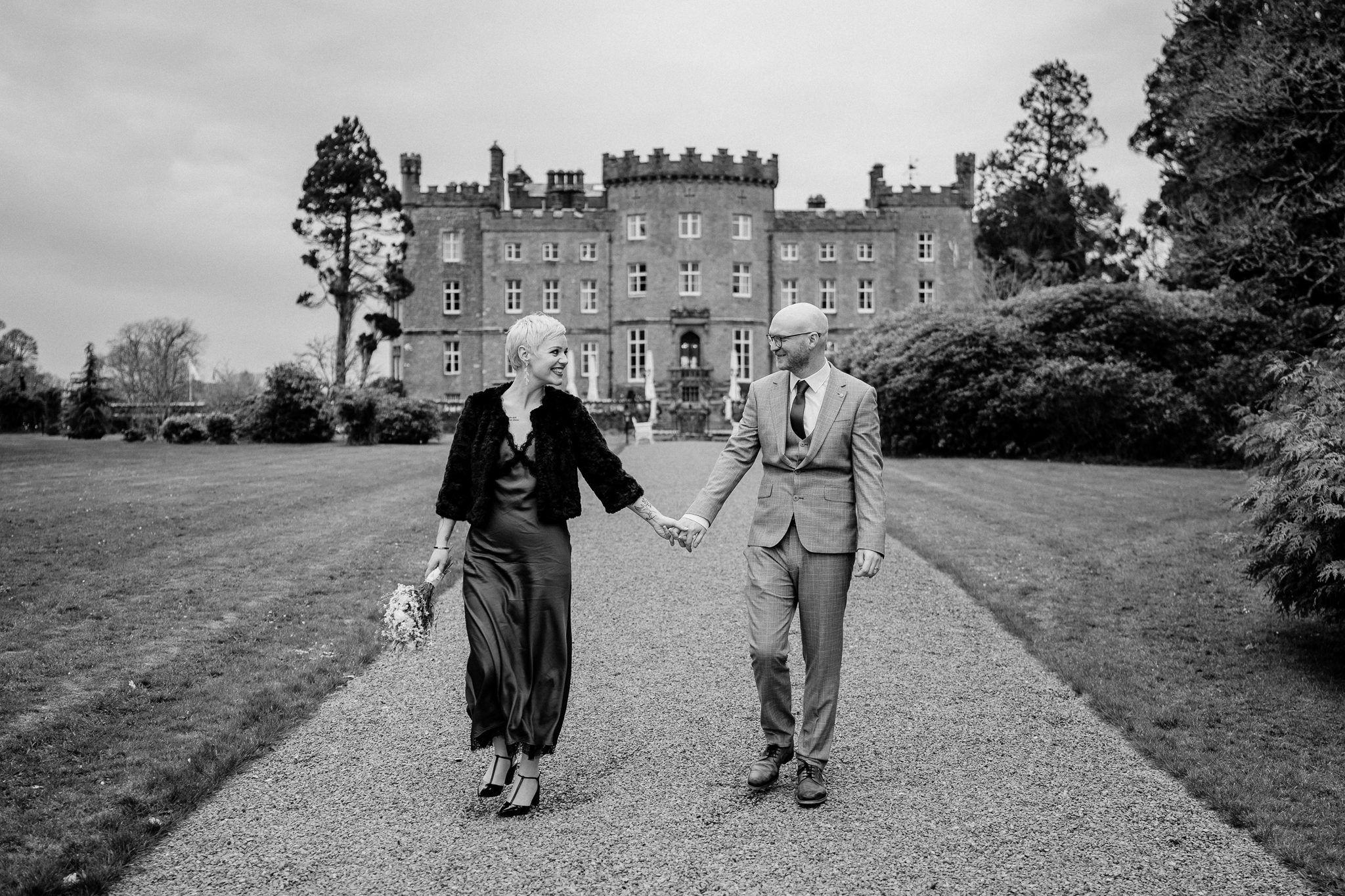 Black and white wedding photograph of newlyweds walking through Markree Castle grounds