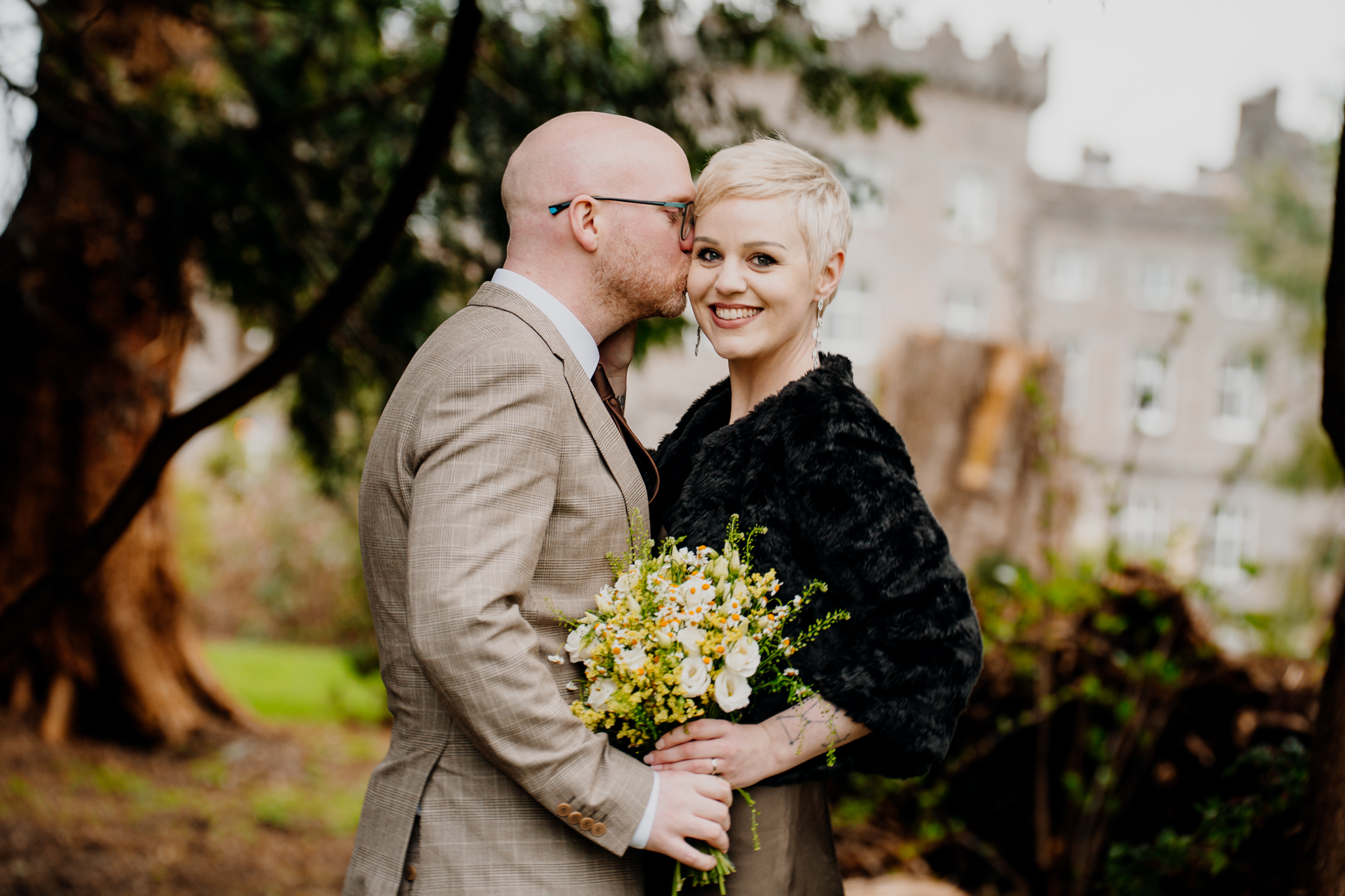 Natural wedding portrait of a couple embracing with a colourful bouquet in Markree Castle woodland
