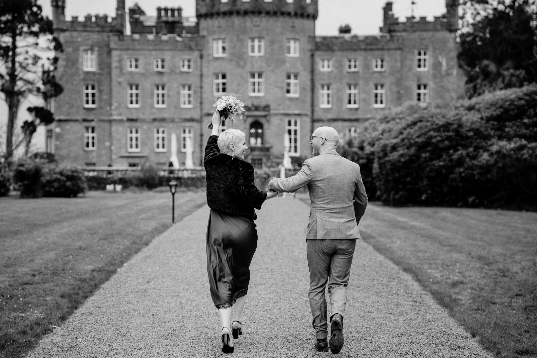 Black and white wedding photograph of newlyweds walking towards Markree Castle in Sligo