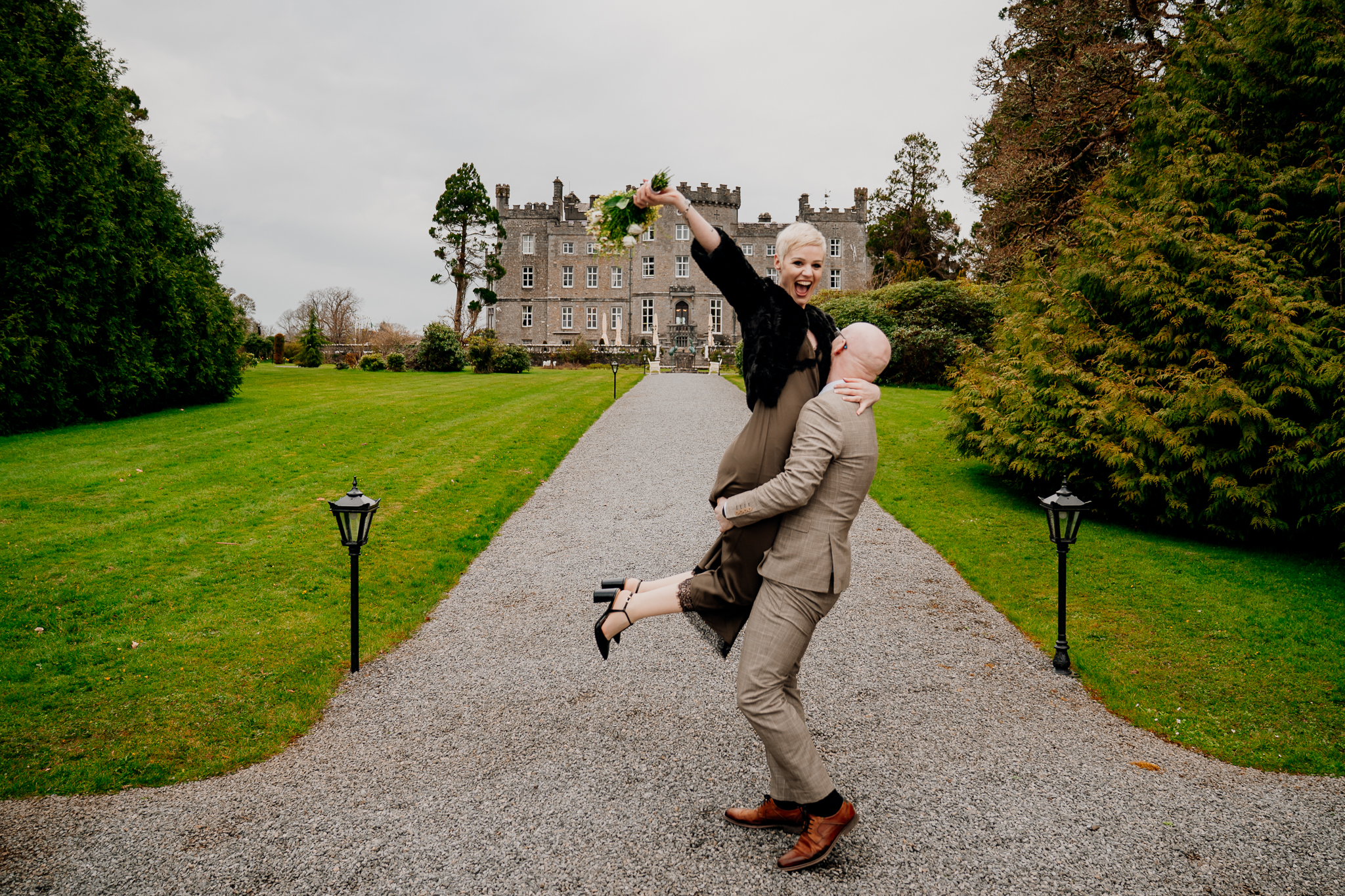 Playful newlyweds celebrating on a garden path in front of Markree Castle Sligo