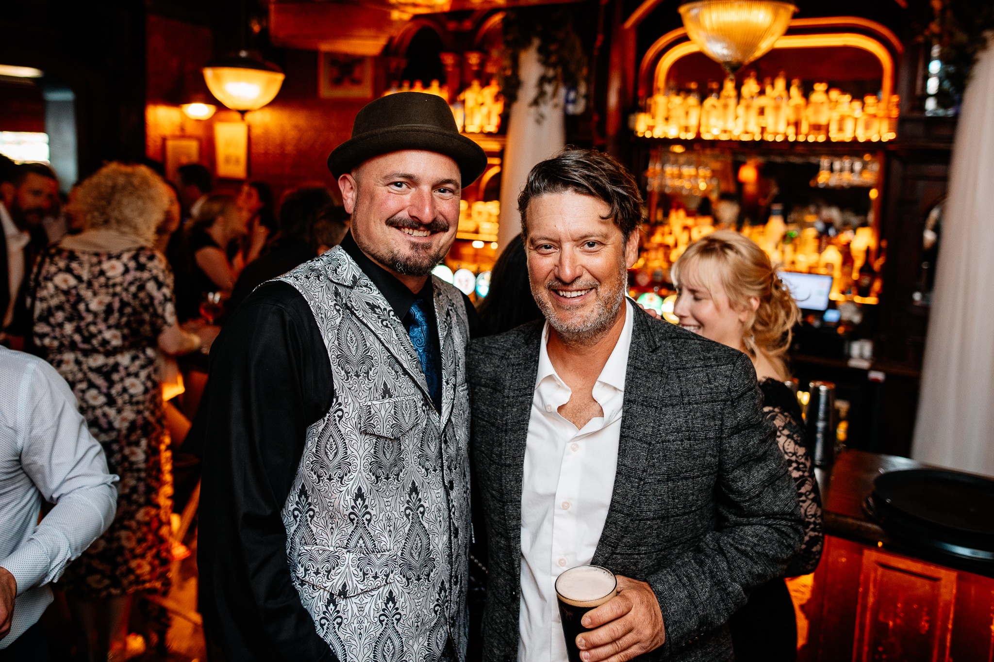 Two smiling male wedding guests posing together inside J.R. Mahon's pub in Dublin