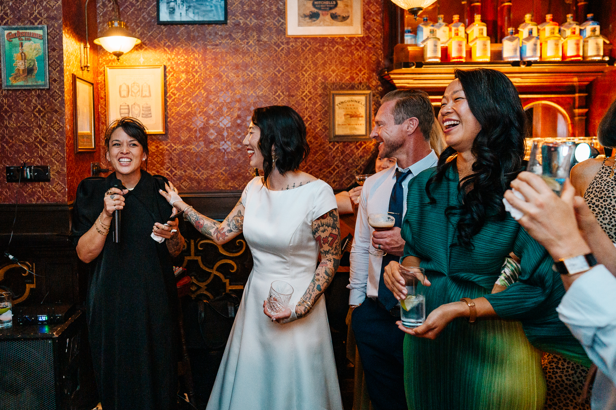 Woman in a white dress standing among smiling guests during a wedding celebration at J.R. Mahon's Dublin