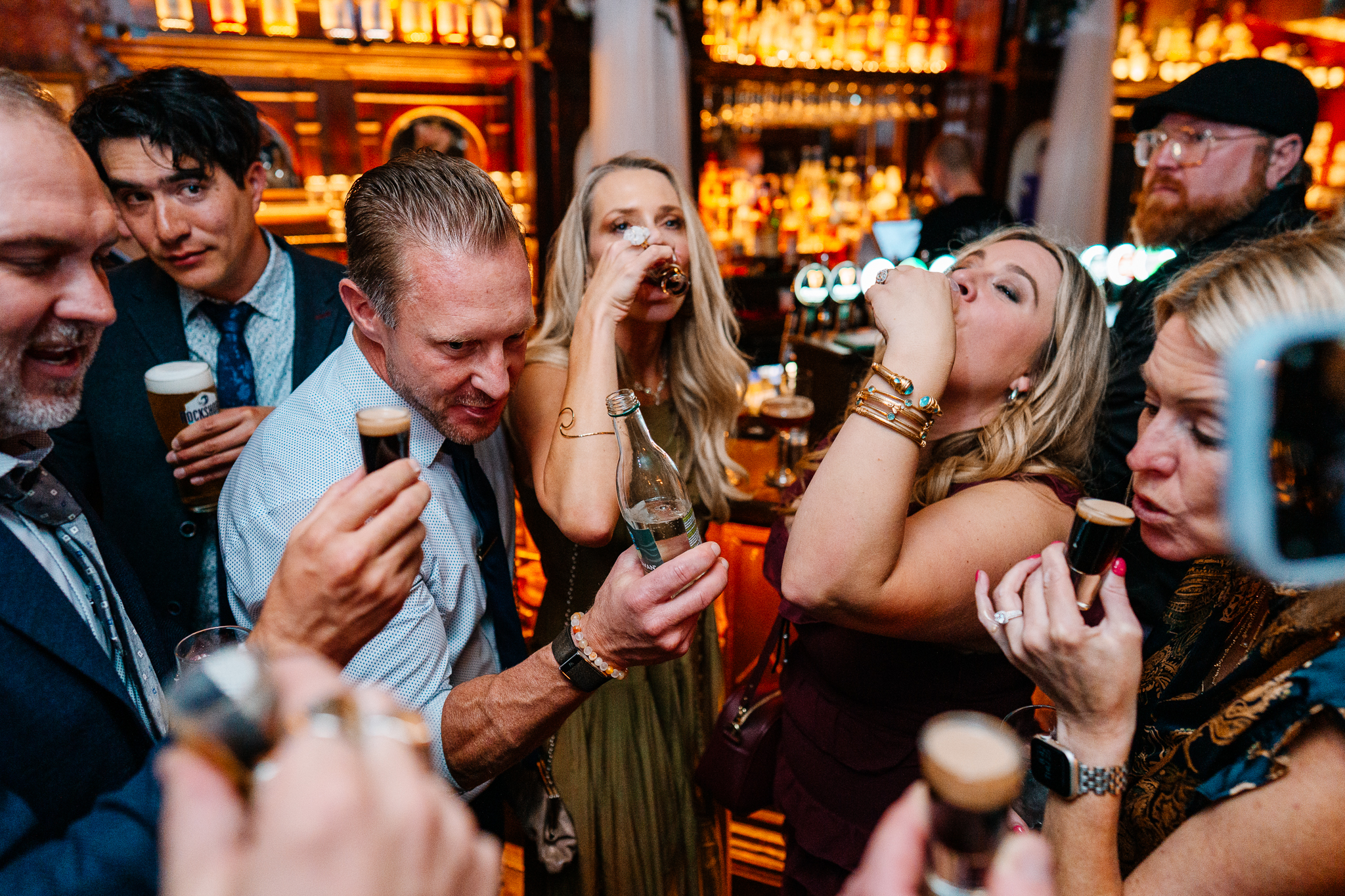 Wedding guests cheering beside a man holding a microphone during a lively reception at J.R. Mahon's Dublin